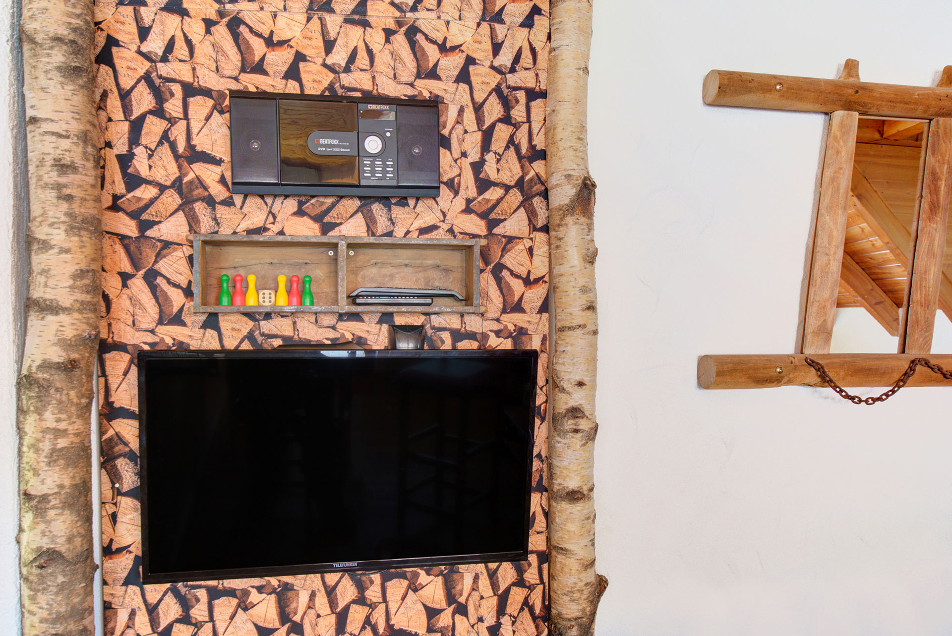 tv monitor mit spielen im regal vor holzwand in ferienhaus