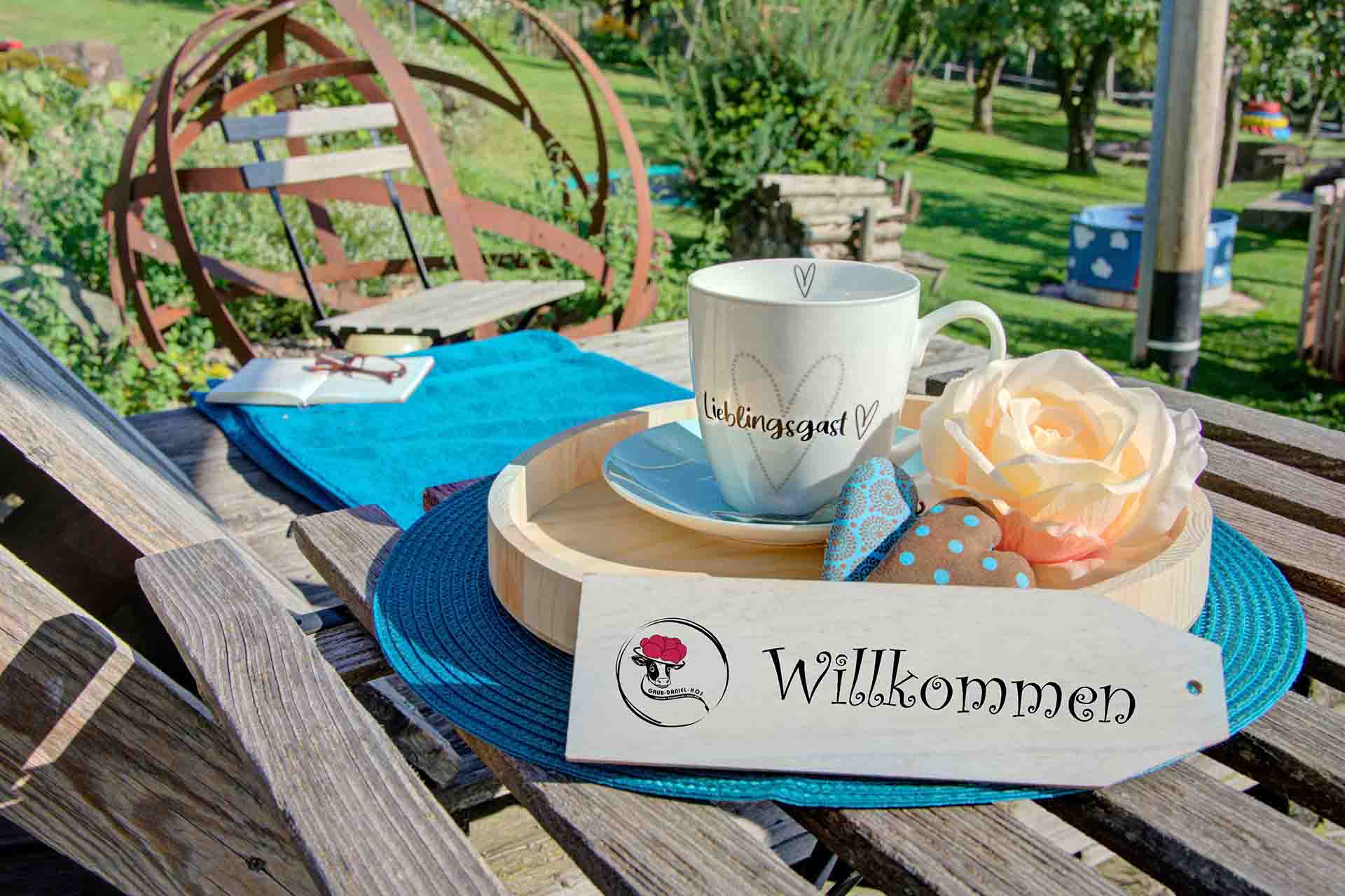 ferienwohnung fotografieren - arrangement aus willkommmesschild vor tablett mit tasse und herzen beim ferienhof