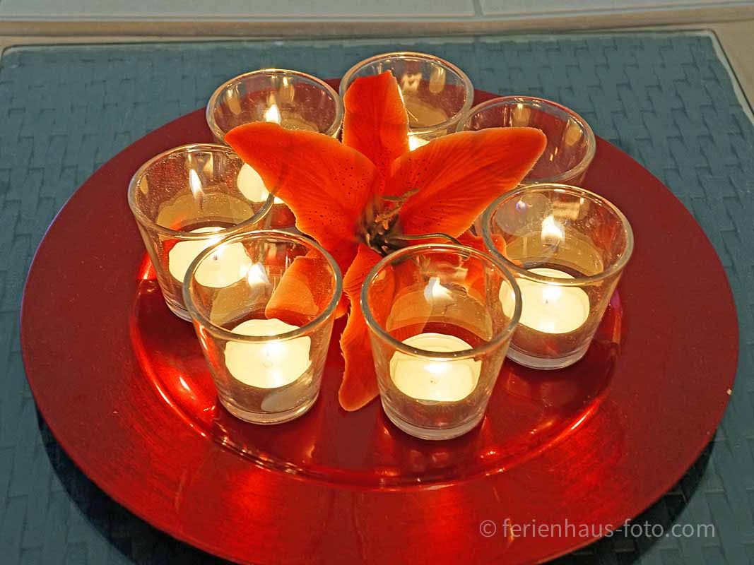 fotografin dekoriert teelichter auf rotem tablett vor türkisem whirlpool
