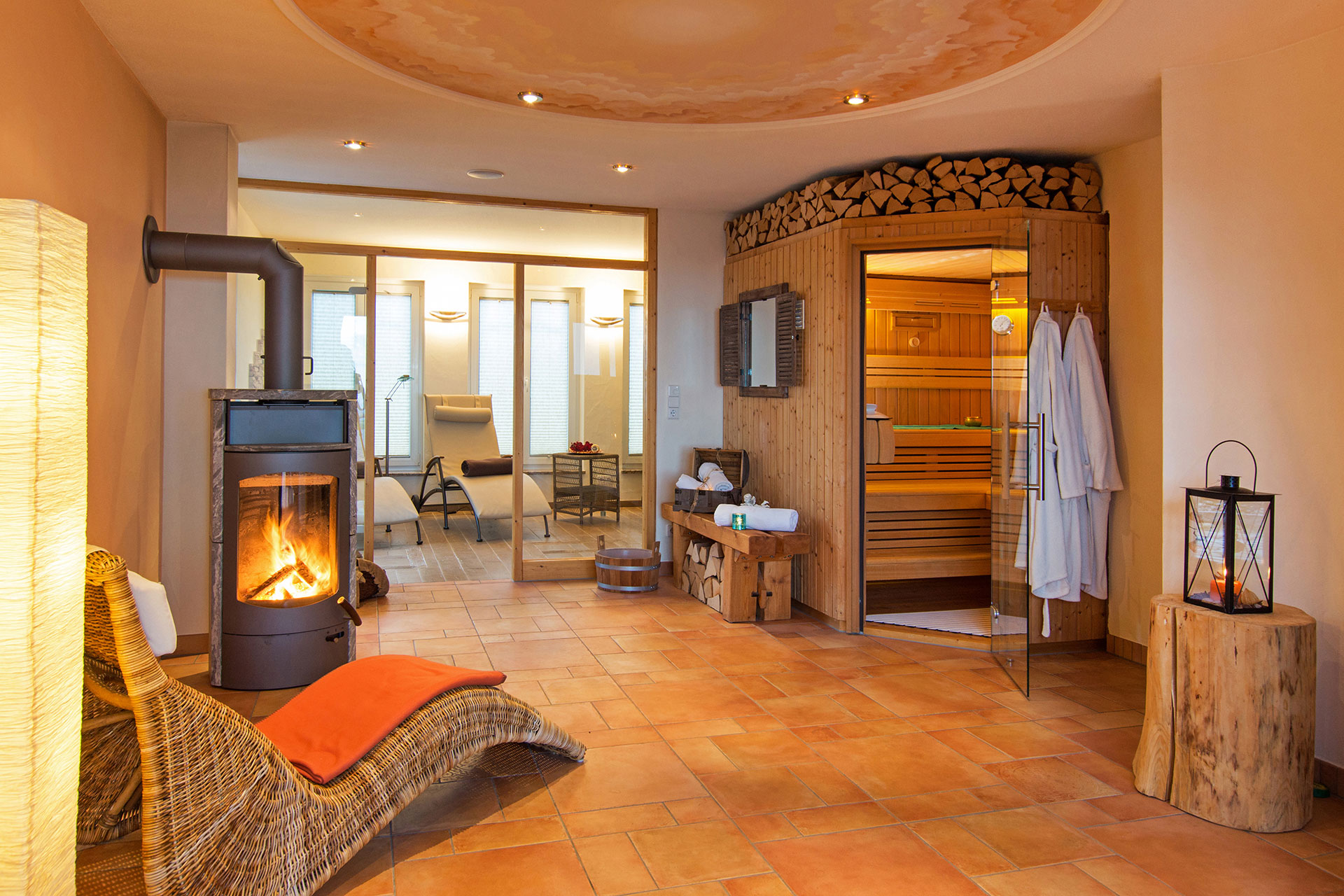 Wellnessbereich des ferienhofes mit leuchtender sauna liegen kaminofen und liegebereich