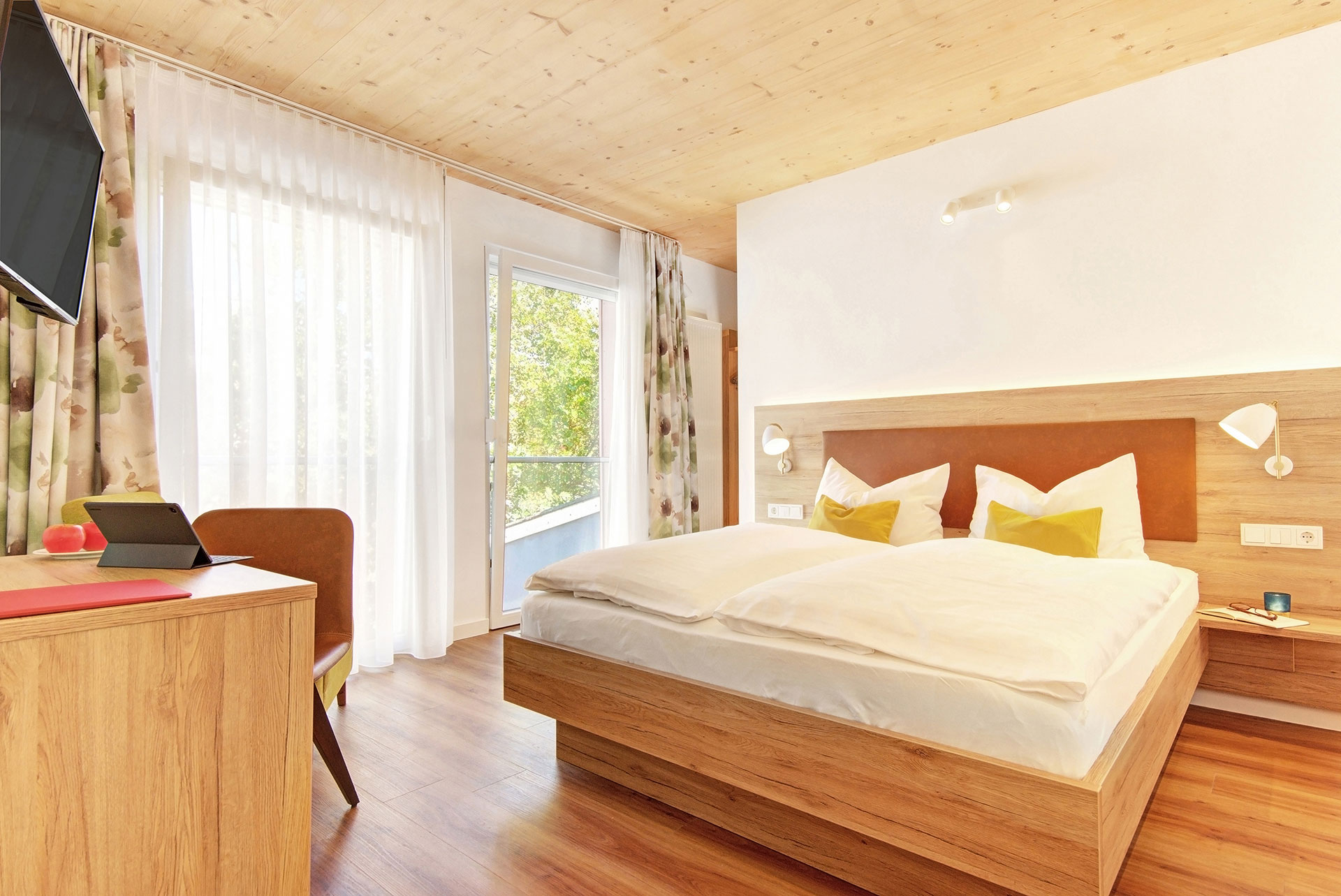 doppelzimmer mit ockerfarbenen kissen blick aufs fenster in hotel