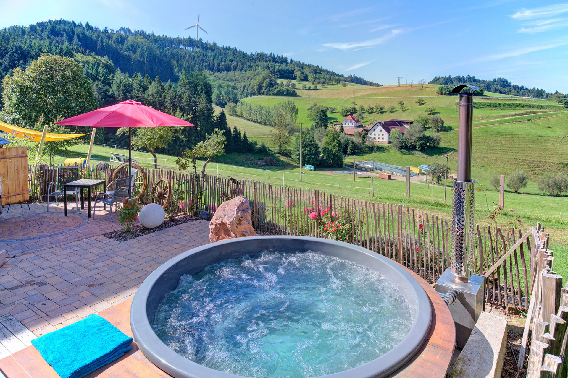 Hot tub mit Blick auf Hügel und blauem Himmel sowie roter Sonnenschirm