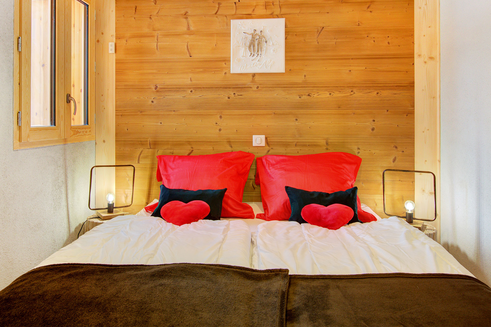 ferienhaus foto doppelbett vor holzwand mit roten herzkissen vor schwarzen kleinen kissen