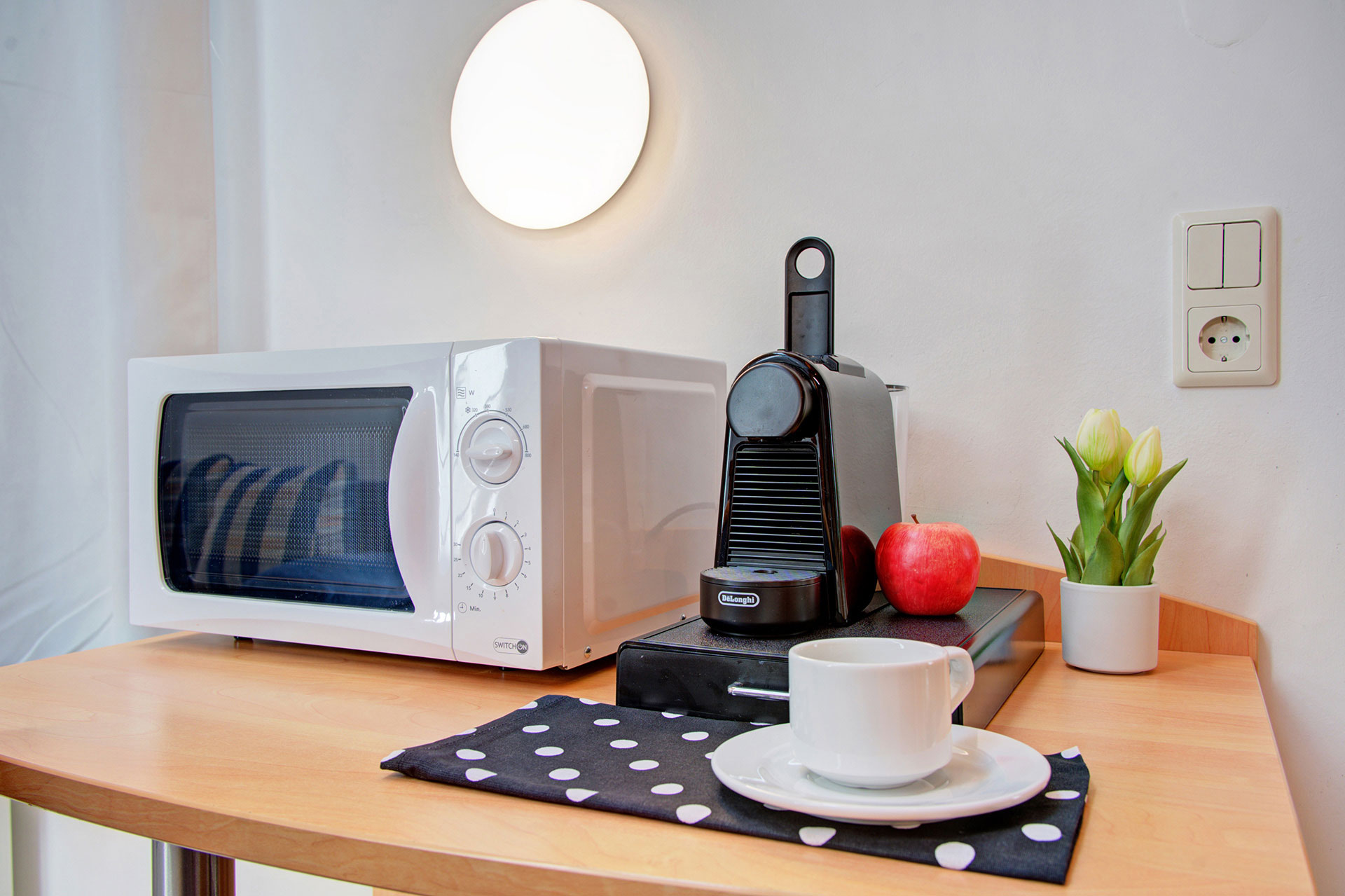 Mikrowelle, espressomaschine und kaffeetasse sowie roter apfel und grünpflanze