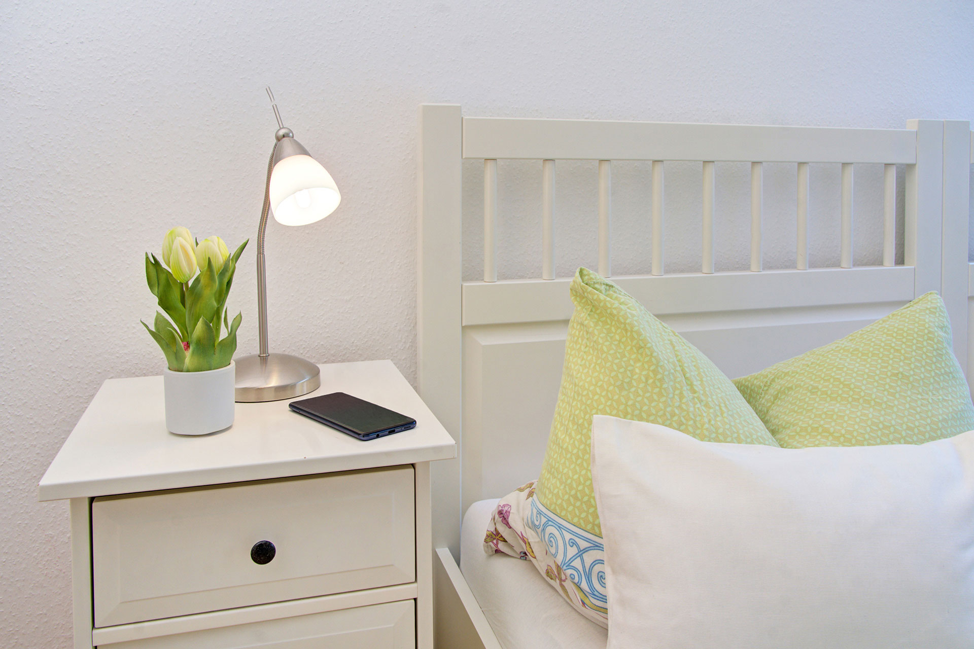 Nachttisch im Ferienhaus mit lampe kleinen Tulpen und smartphone