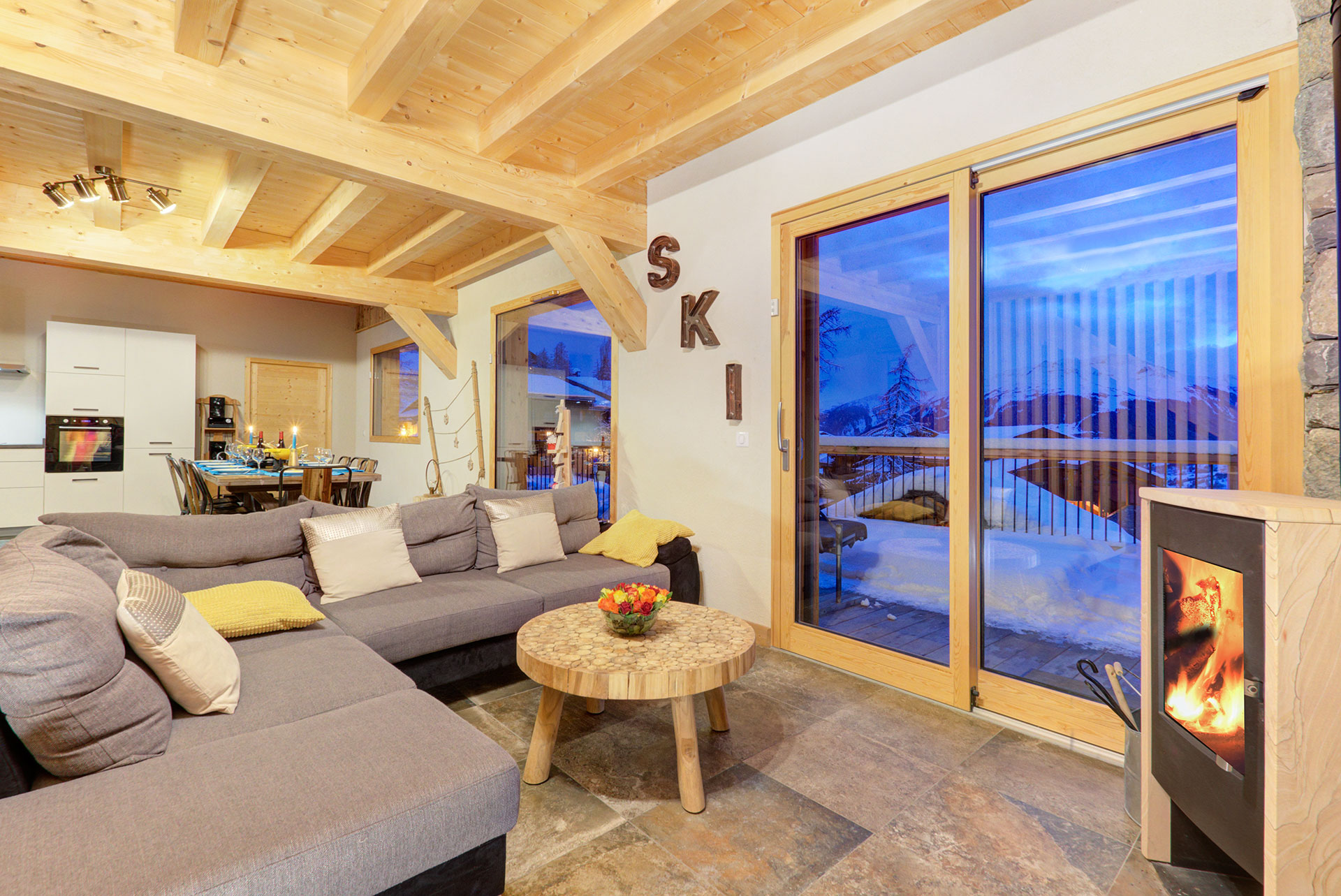 Wohnraum am Abend mit Blick auf Schneeberge von Chalet Ski Dream