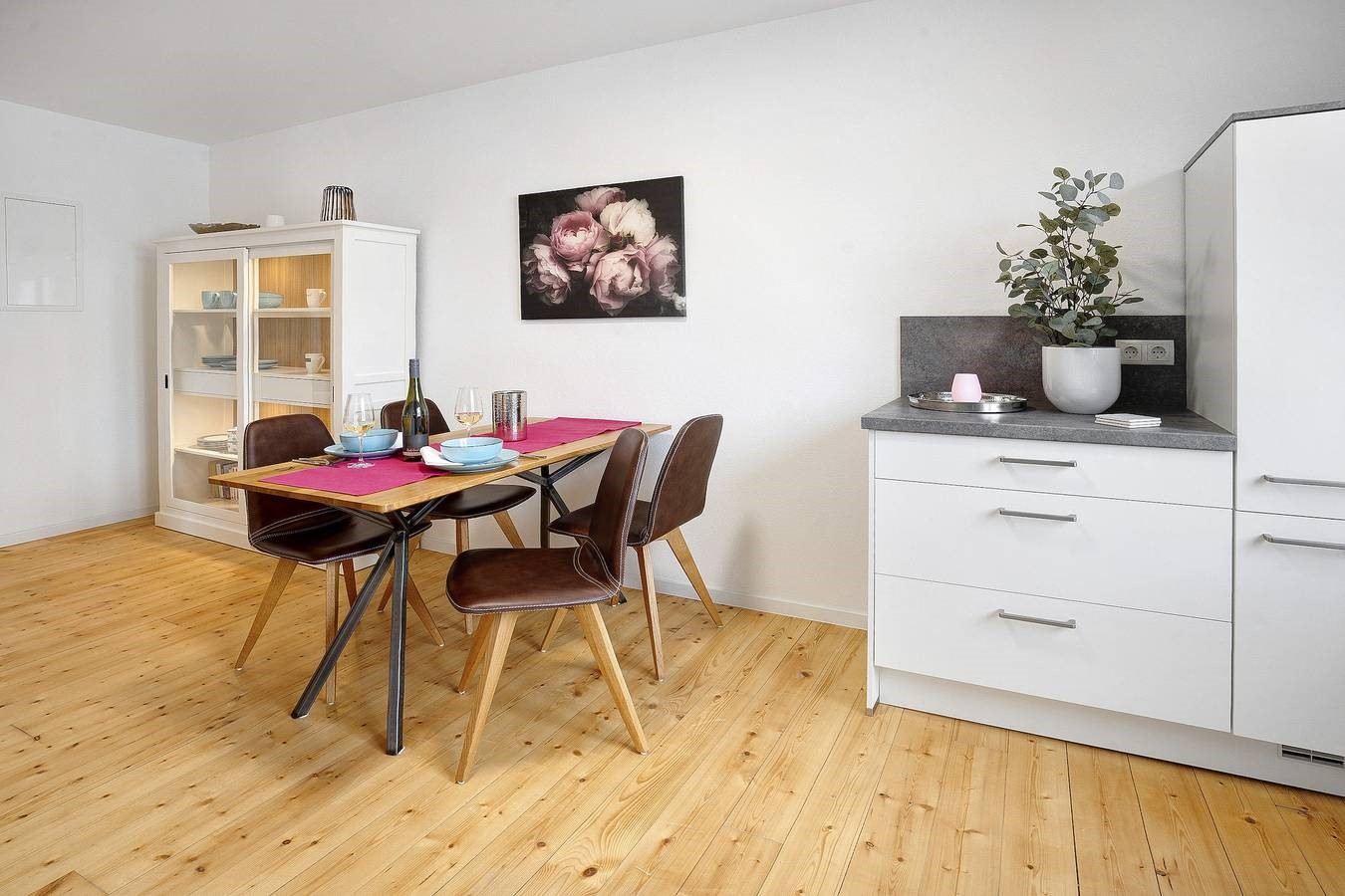 Esstisch mit pink gedeckter tisch und mit türkisfarbenen servietten sowie sideboard