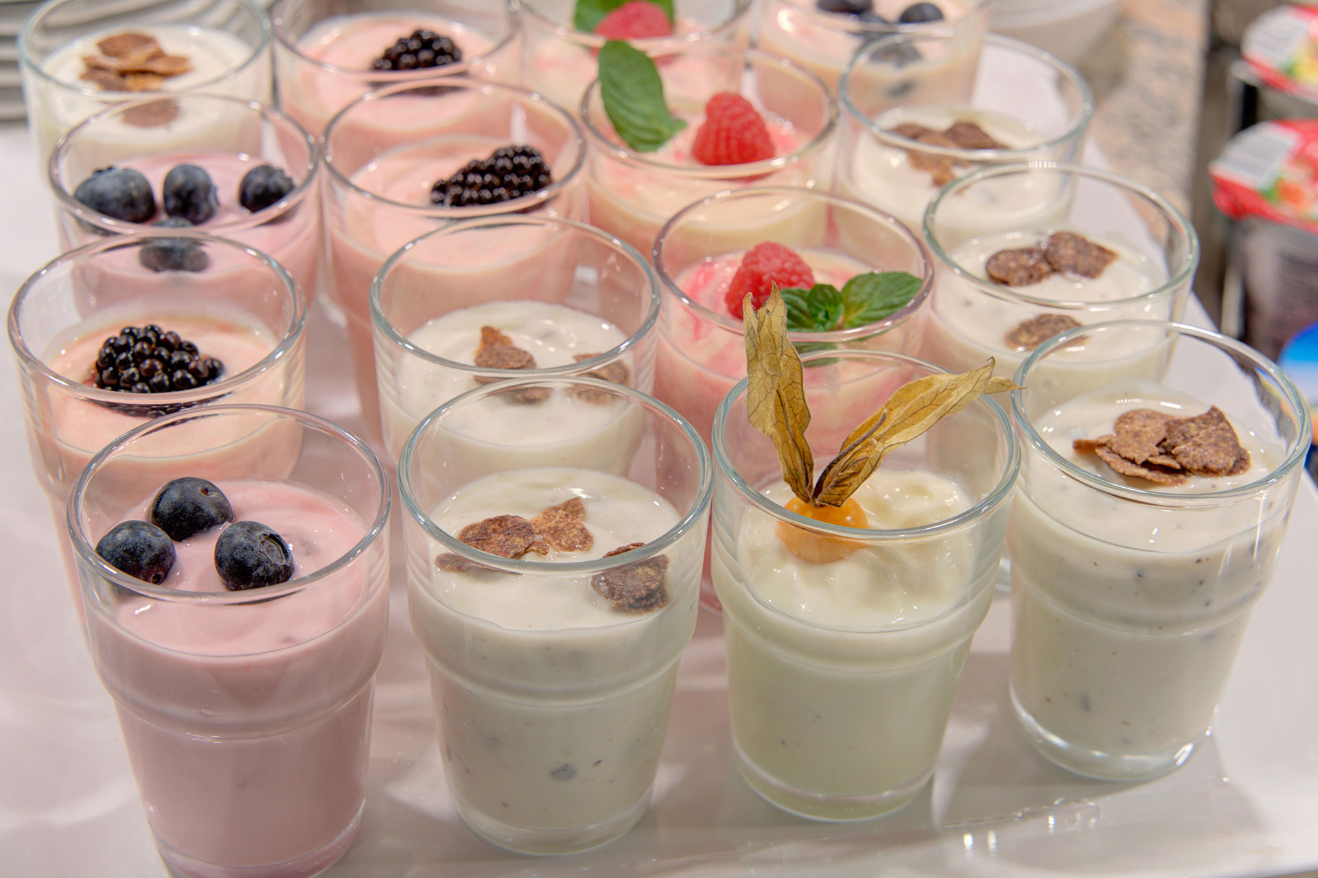 joghurtgläser mit beeren und physalis im hotel fotografiert