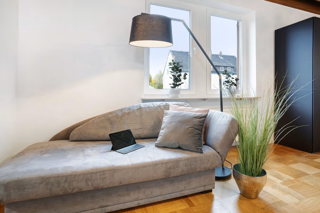 Graue Recamiere mit Stehlampe und laptop sowie blick zum fenster