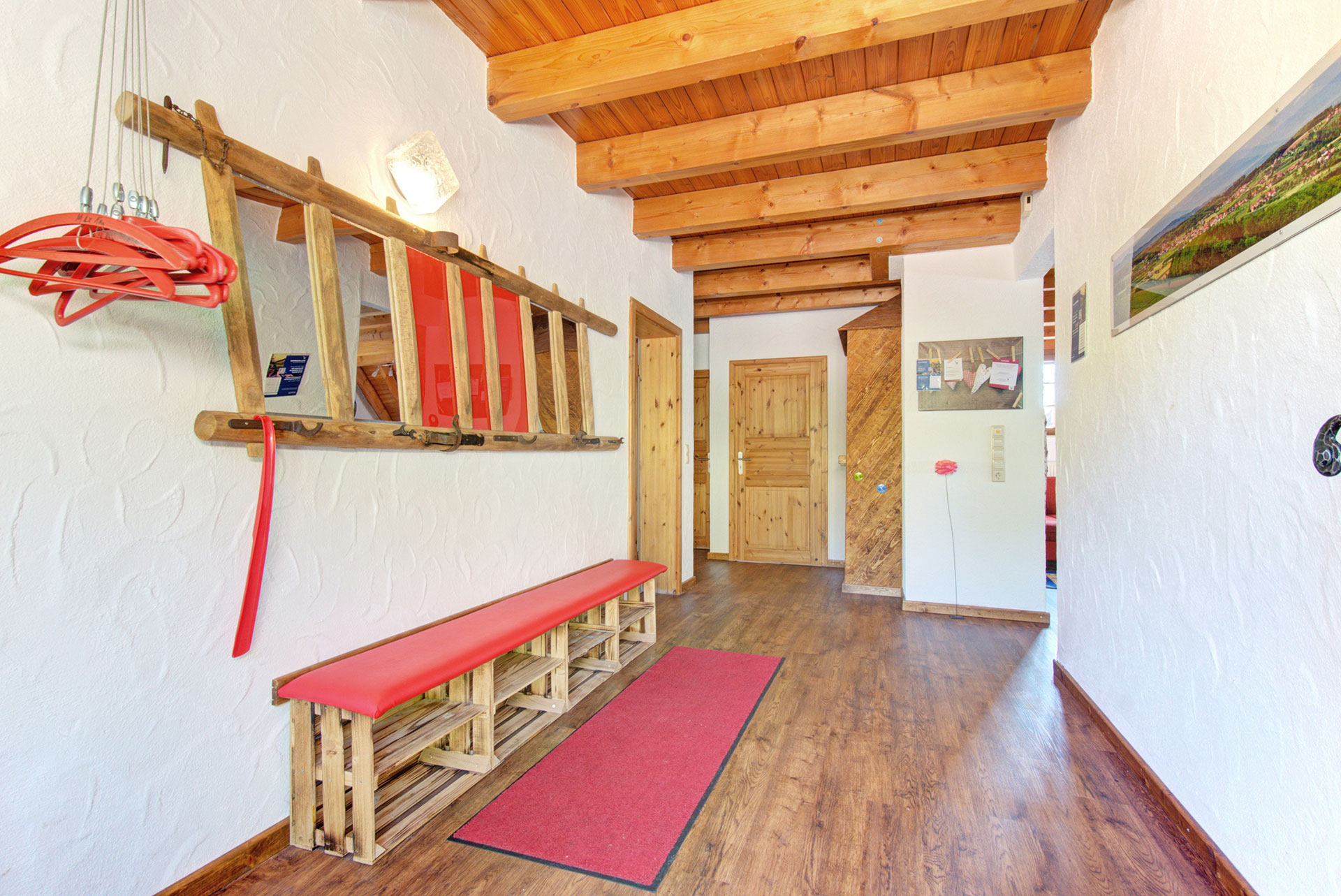 hausflur mit roter sitzbank und garderobe im ferienhaus
