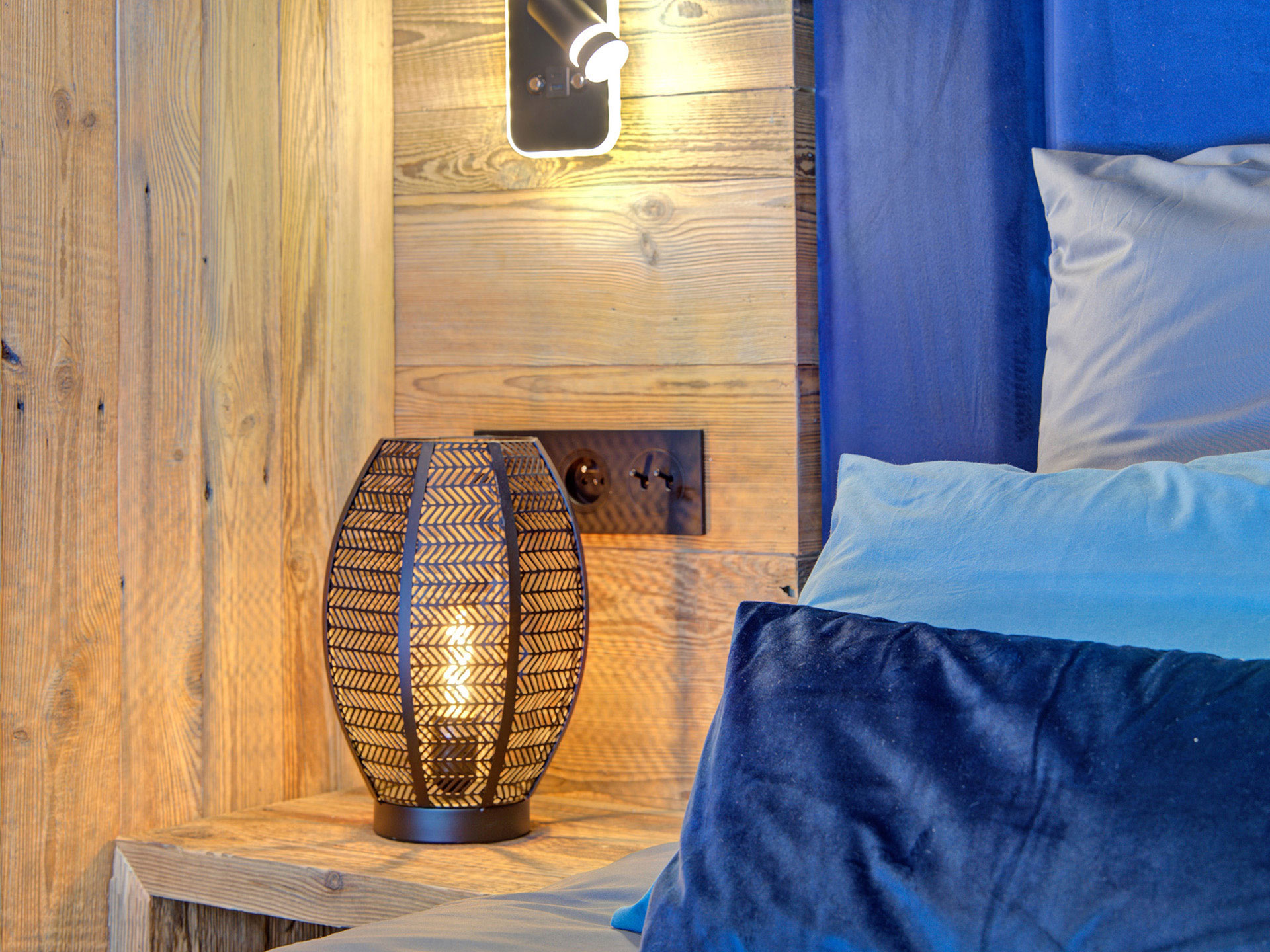 holznachttisch mit schwarzer lampe und ein blaues sowie türkises Kissen