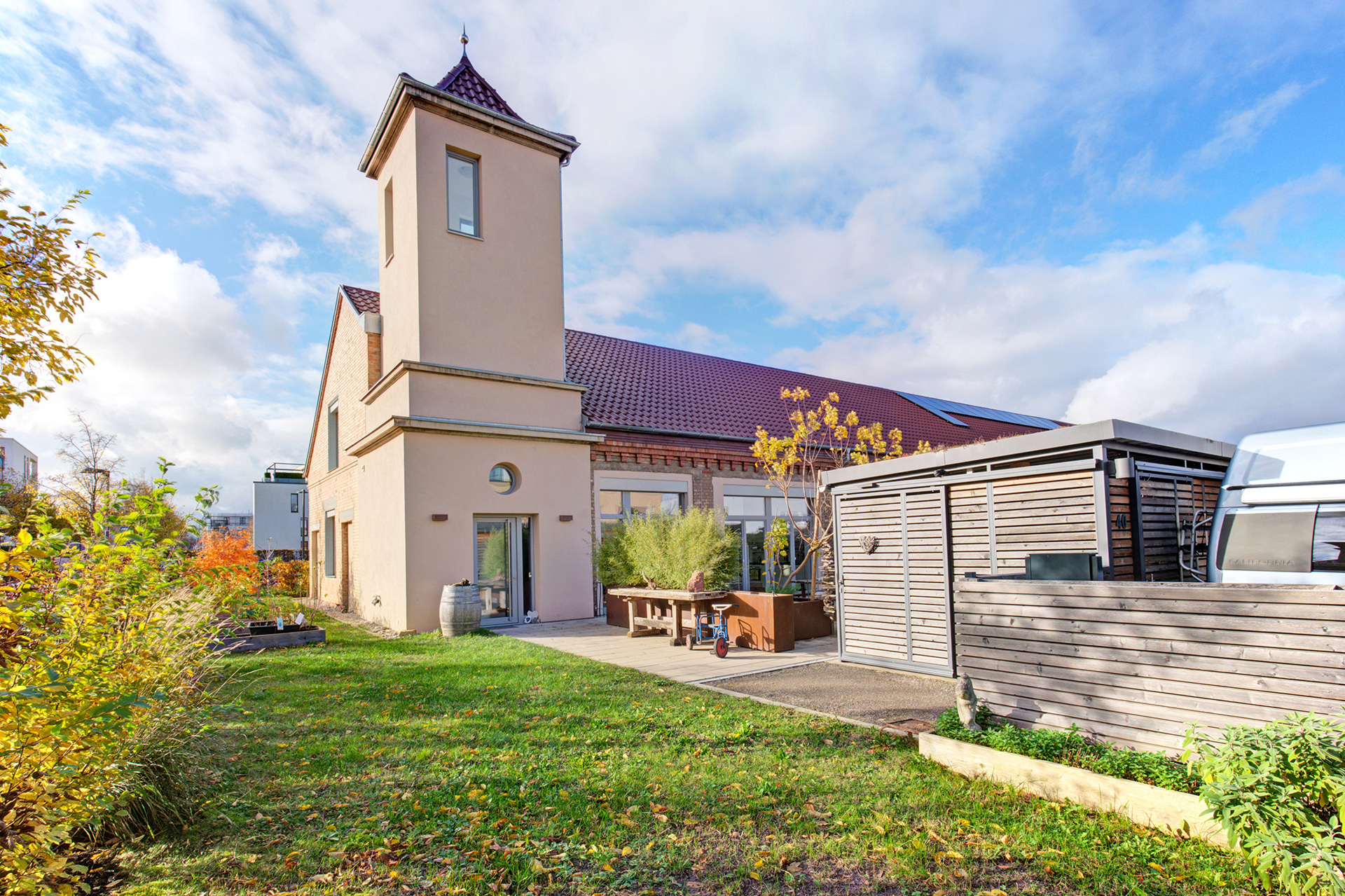 hochwertiges Immobilienfoto - Historisches Reihenendhaus mit Turm bei blauem Himmel im Herbst