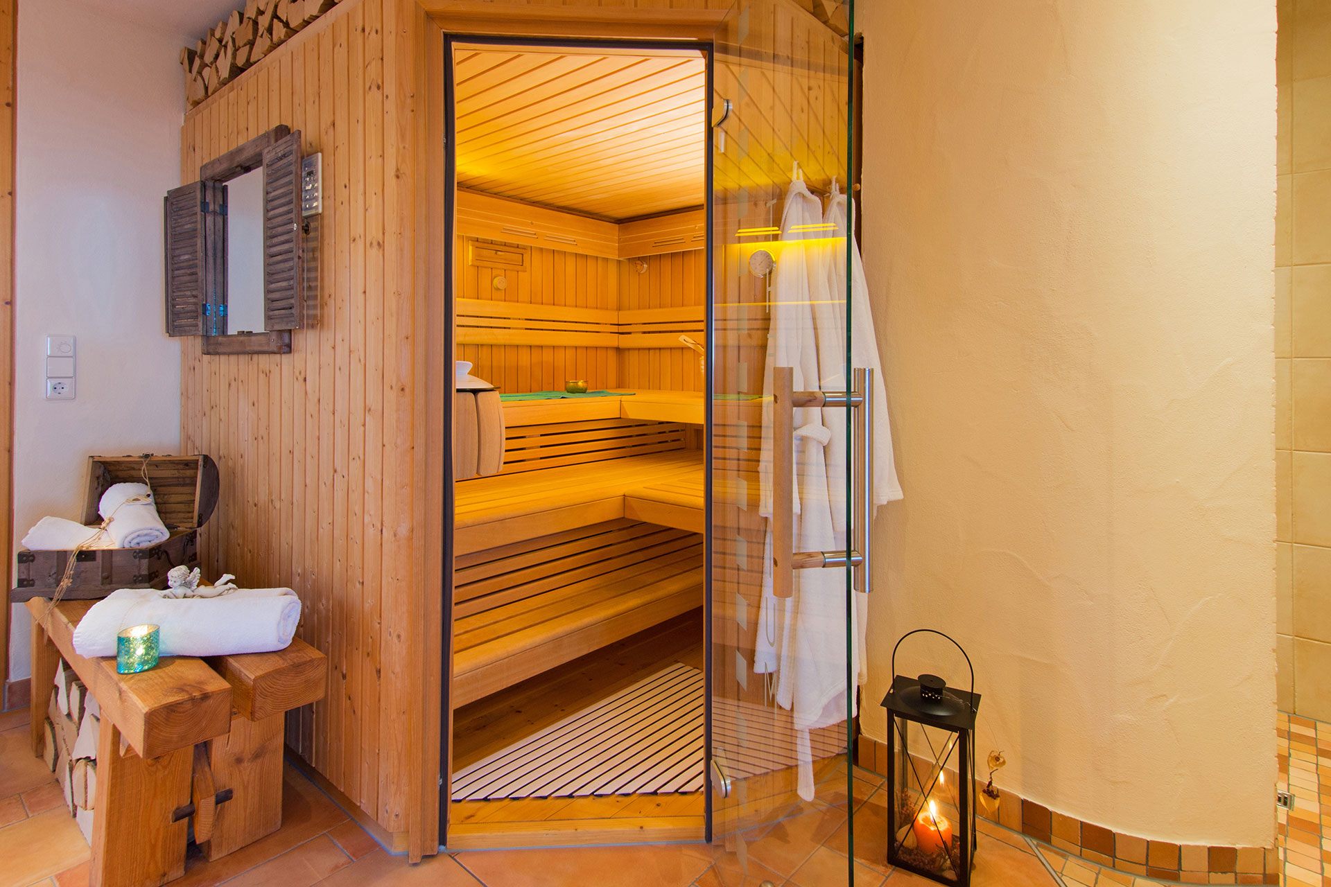 leuchtende sauna mit offener tür mit bademantel und laterne beim ferienhof