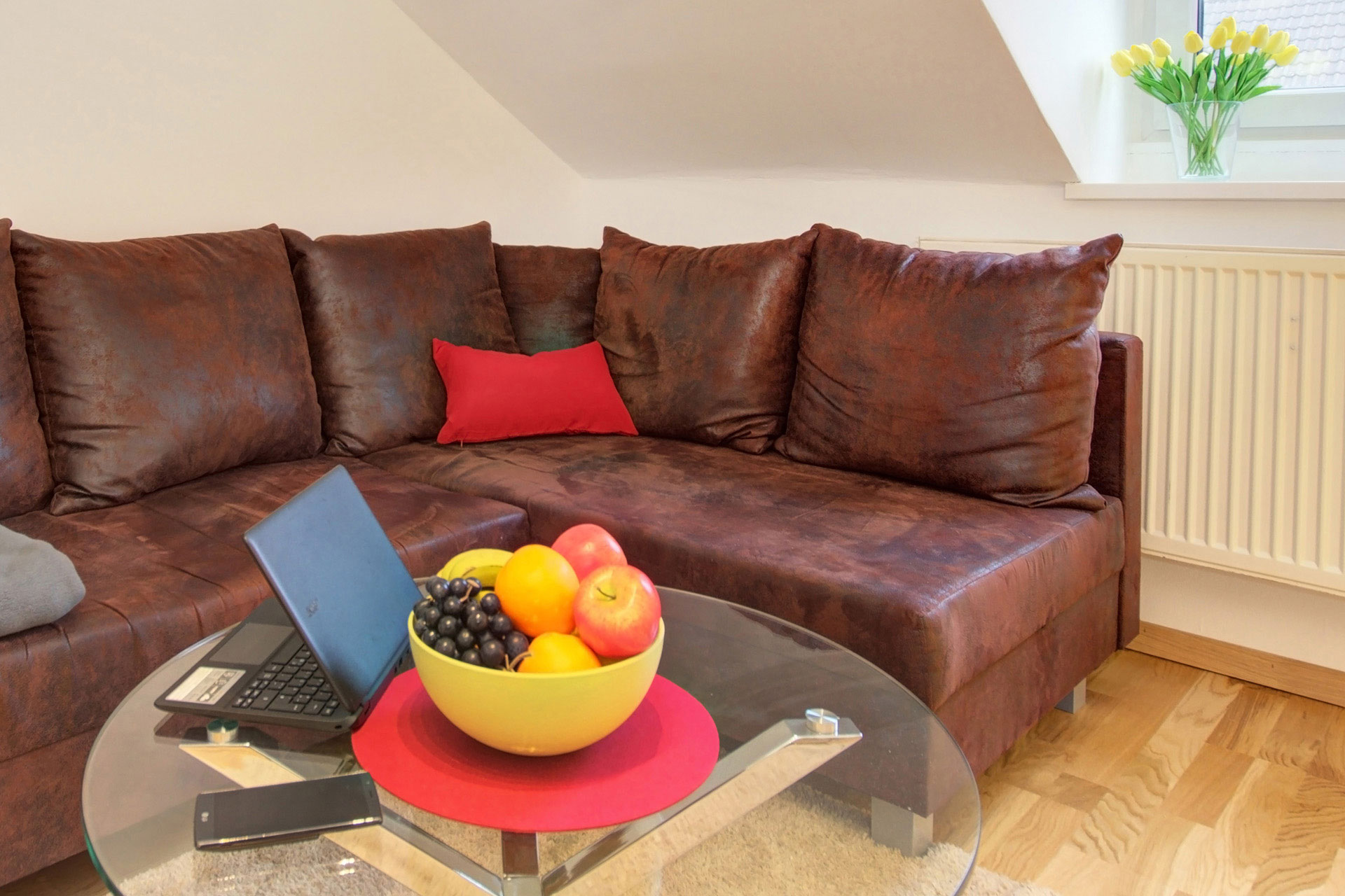 fotografin dekoriert braunes sofa mit glastisch und tablet smartphone sowie obstkorb