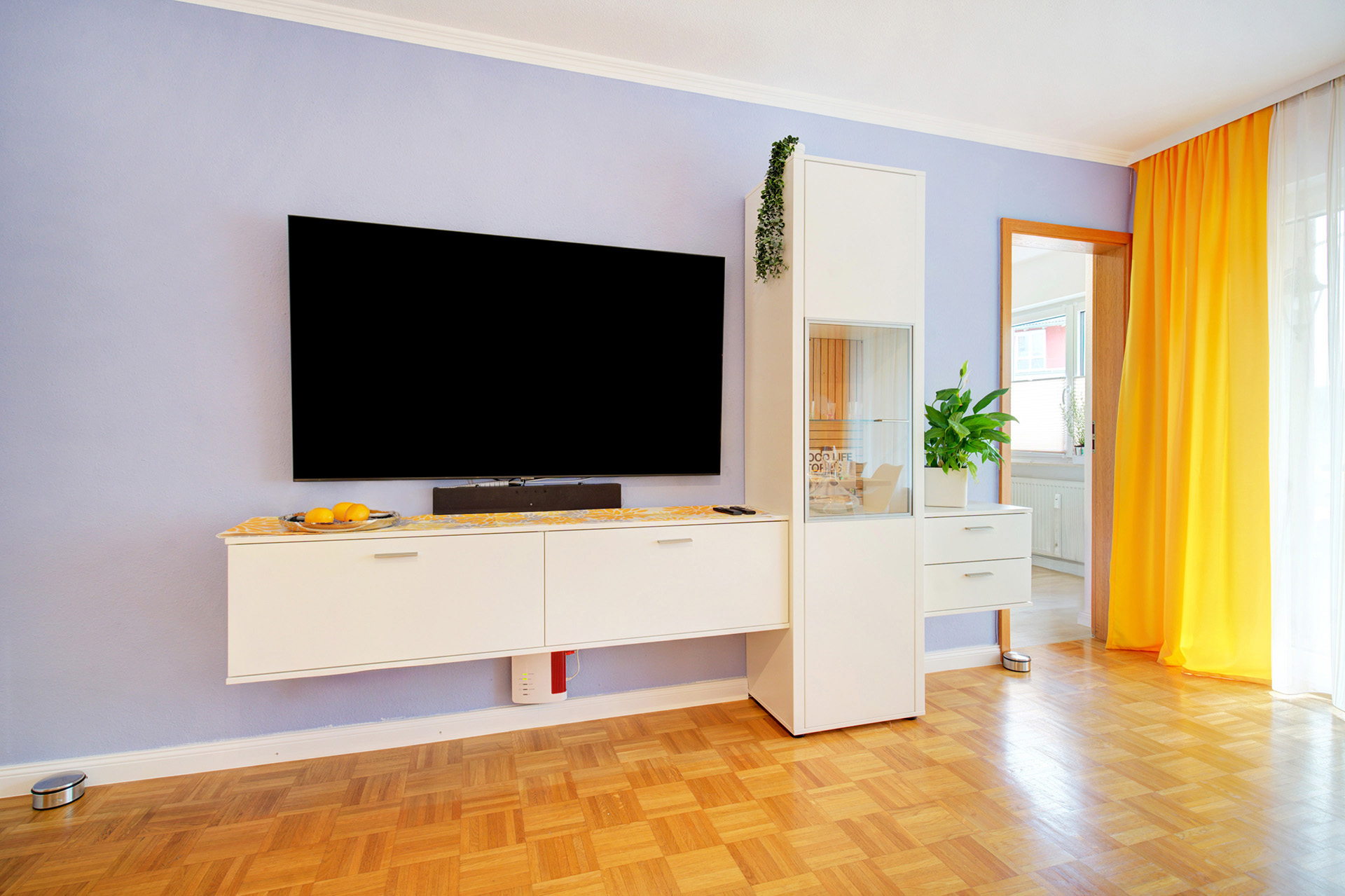 breiter tv-monitor mit hochschrank in wohnzimmer mit blick auf küche