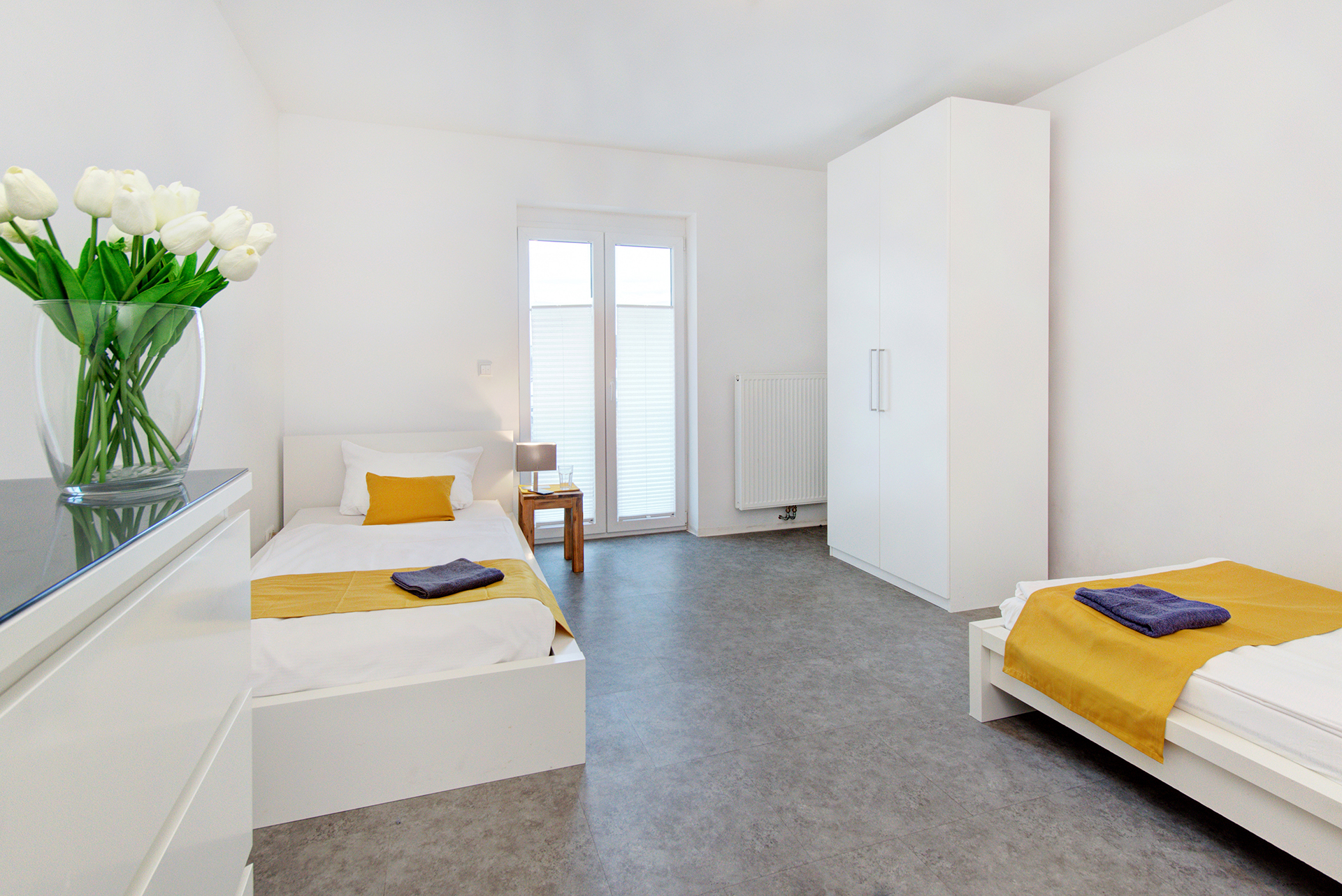 monteurzimmer fotografieren zimmer mit zwei einzelbetten mit okker bettläufern seitlich tulpenstrauss