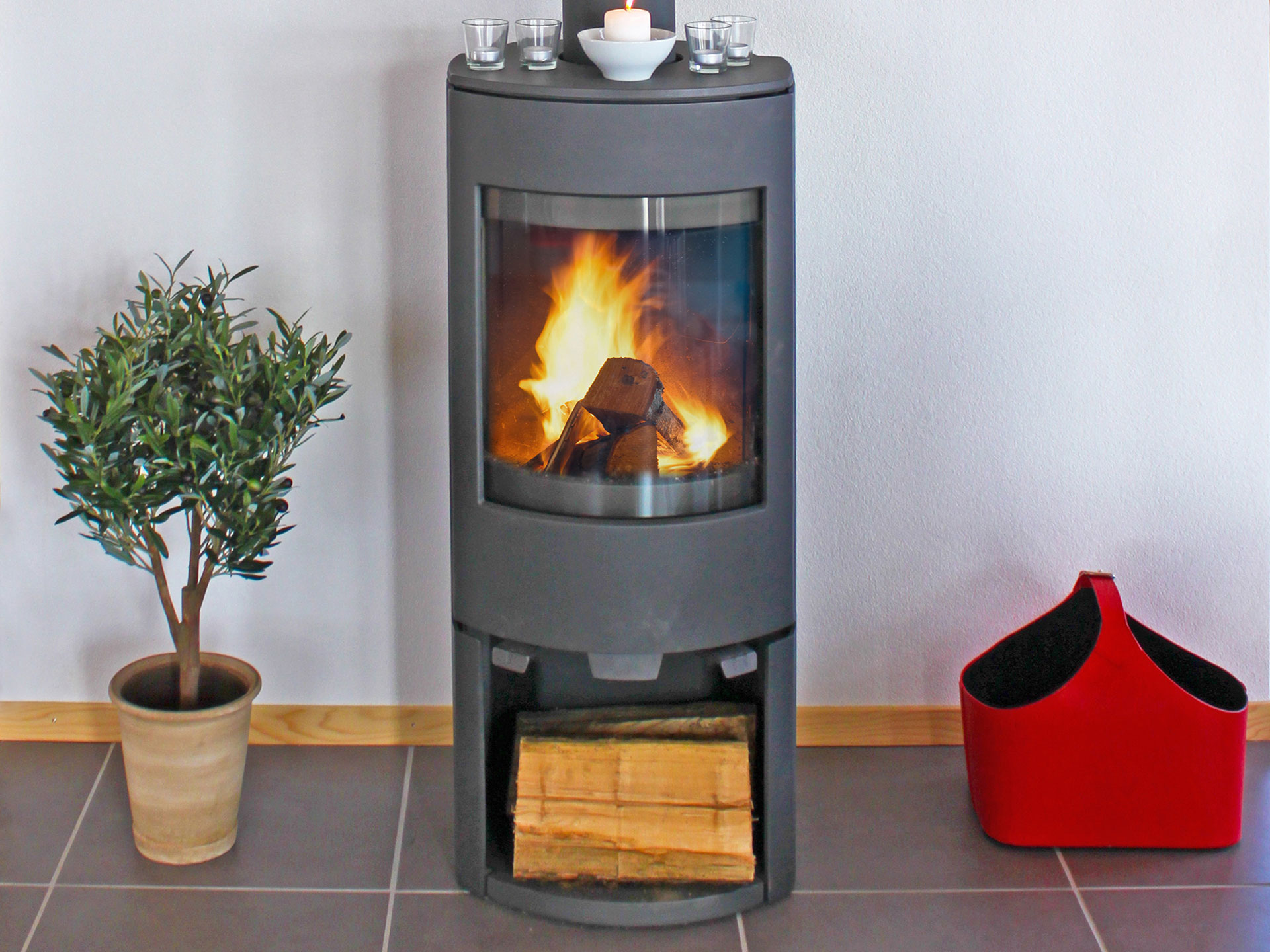 zentraler brennender Schwedenofen in ferienhaus, klare linien - mit pflanze, holz und filztasche - nachher mit bildbearbeitung