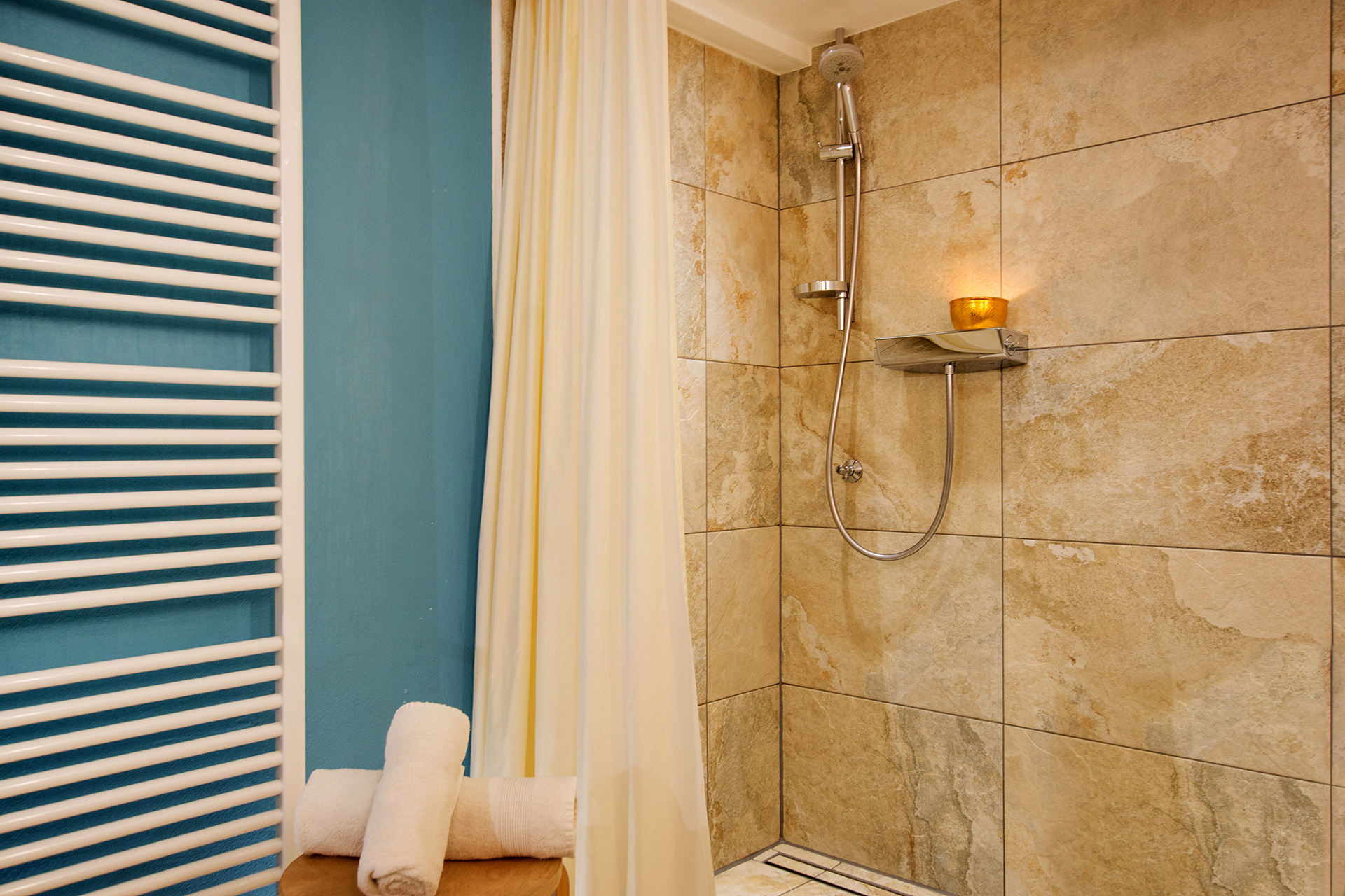 Barrierefreies badezimmer mit hocker und steinfliessendusche in ferienwohnung