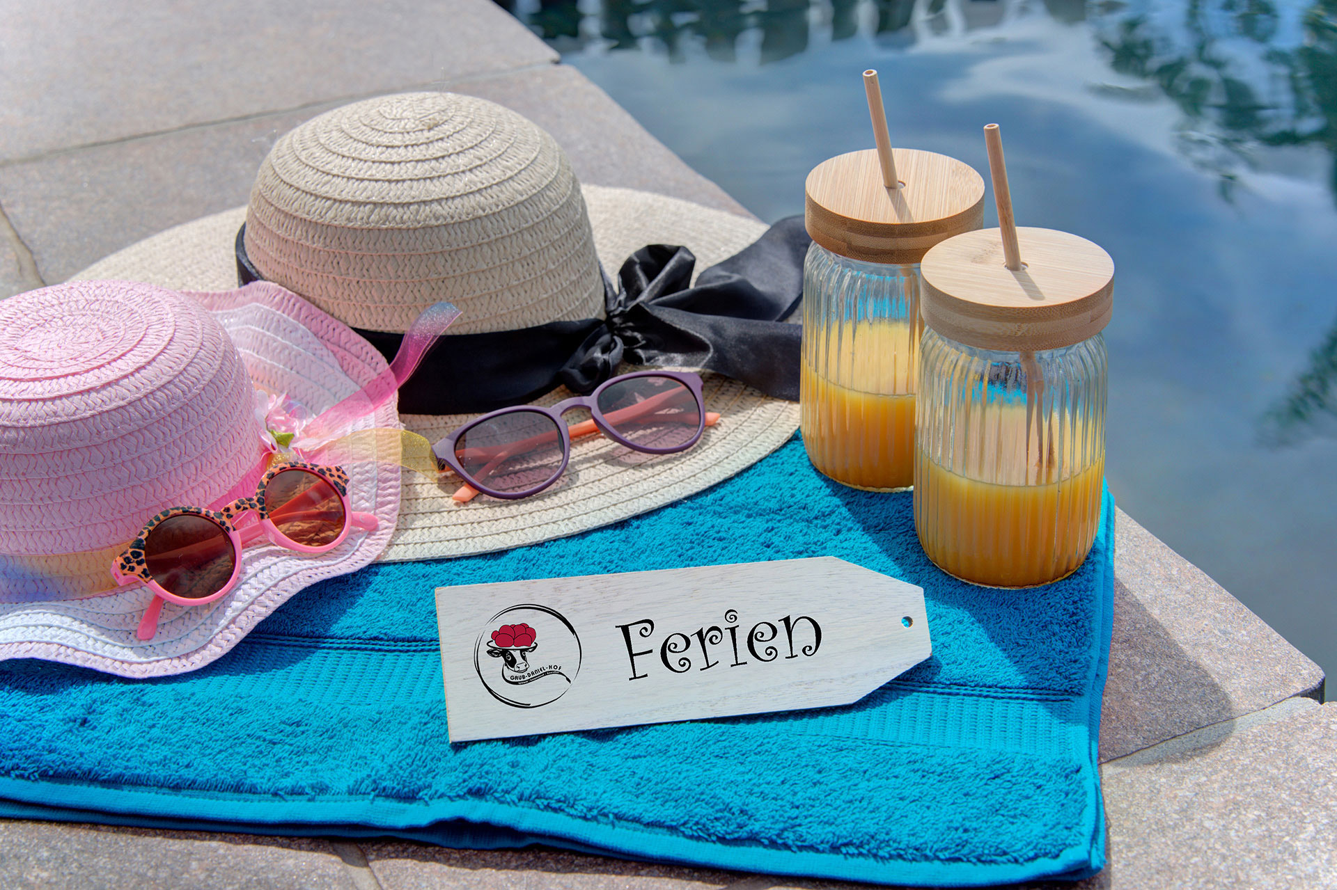 Sonnenhüte am pool mit Getränken und Schild Ferien im Ferienhof
