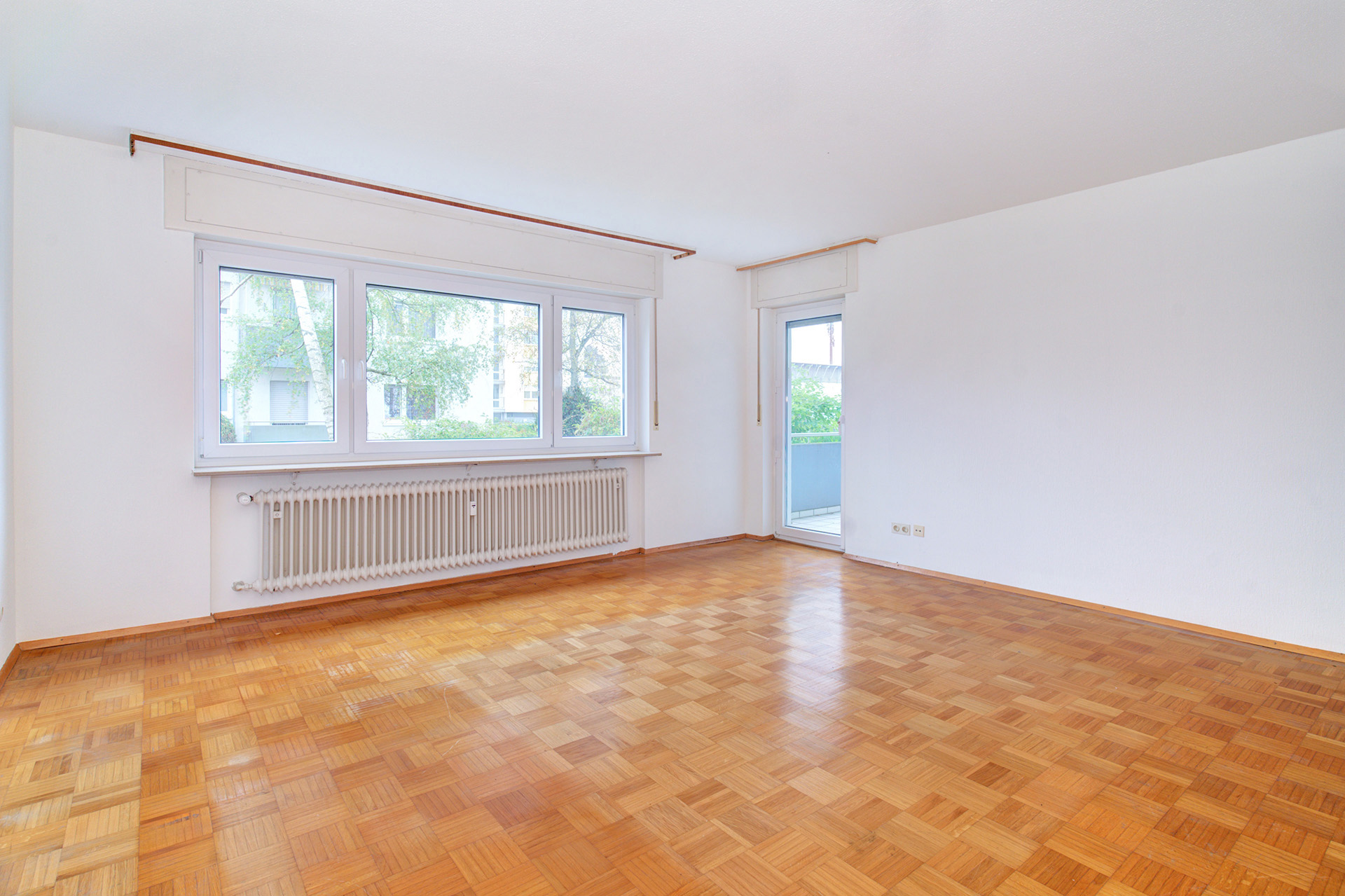 Leerer Wohnraum mit holzboden und blick zur Balkontür
