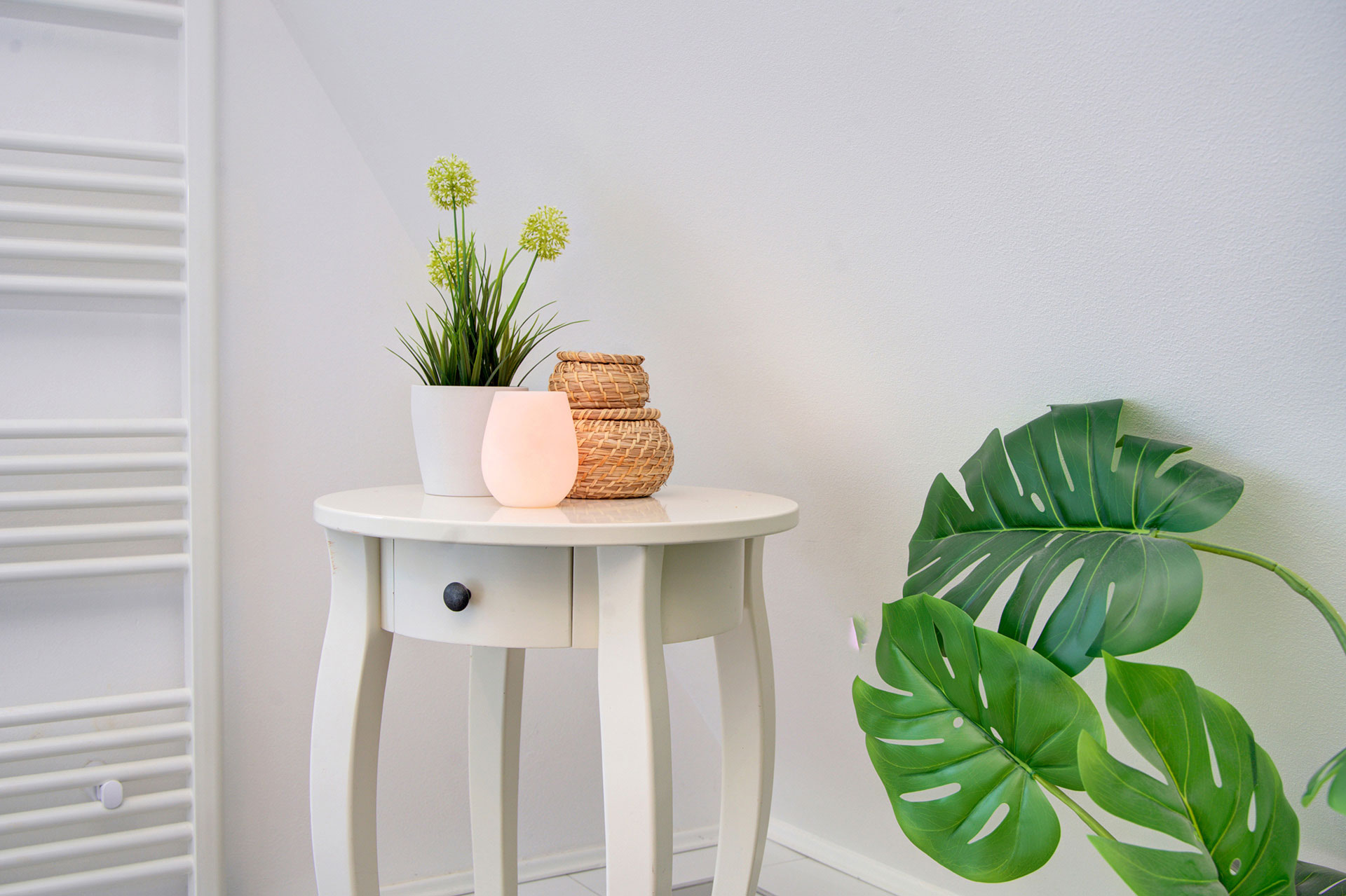 detailbild tisch mit lampe grünpflanze und seitlich montsera in ferienhaus