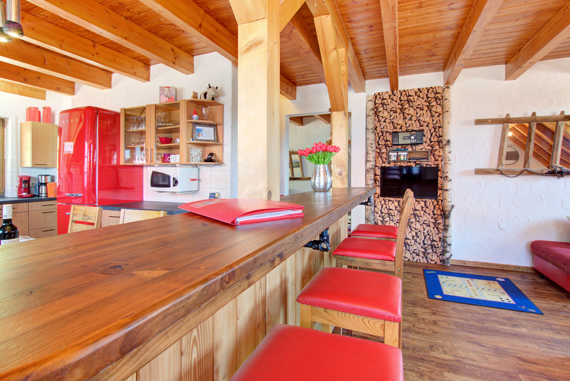 grosse sitztheke aus holz mit roten stuhlauflagen im Ferienhaus