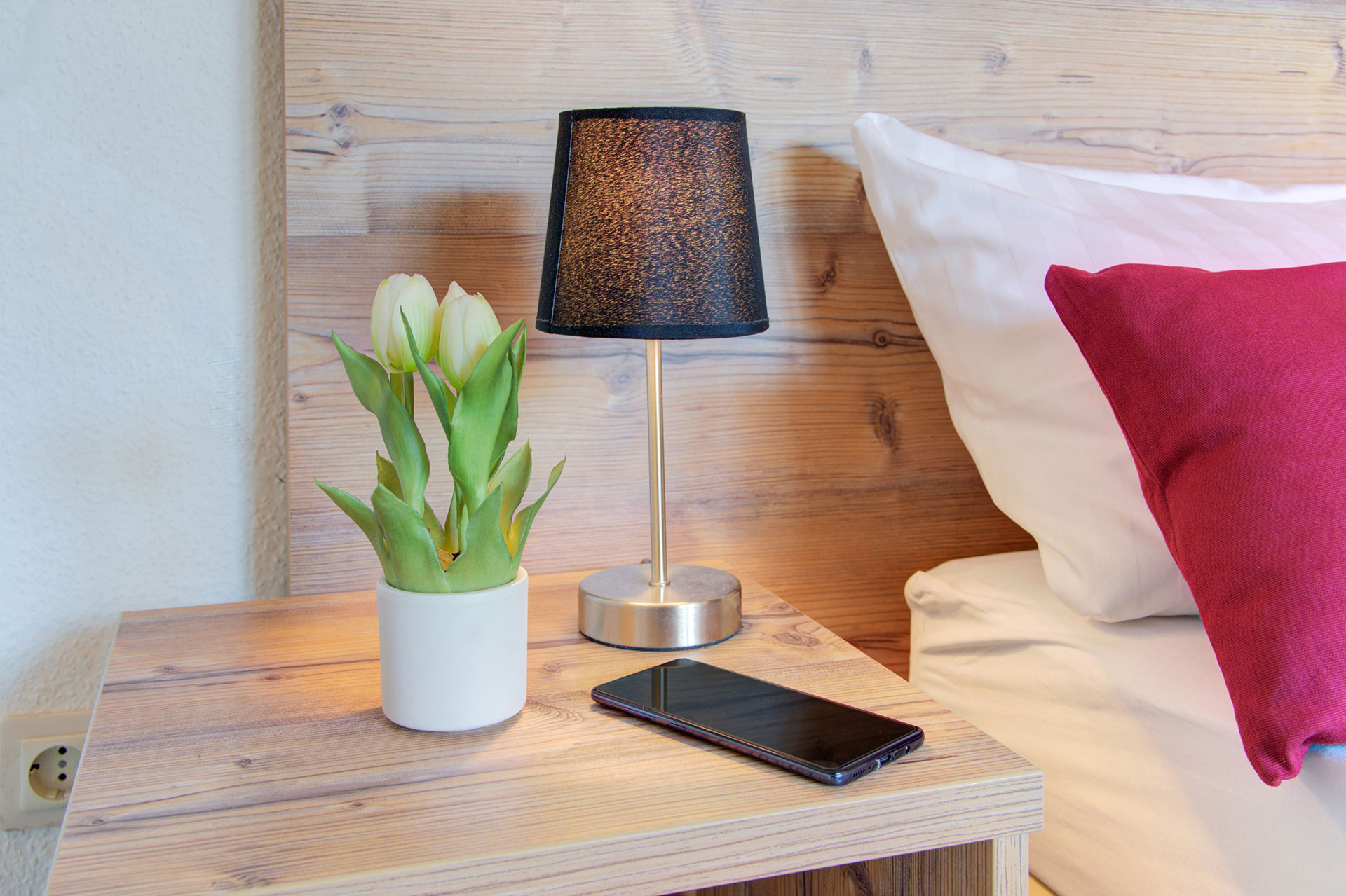 nachttisch mit tulpe smartphone schwarze kleine lampe in ferienhaus