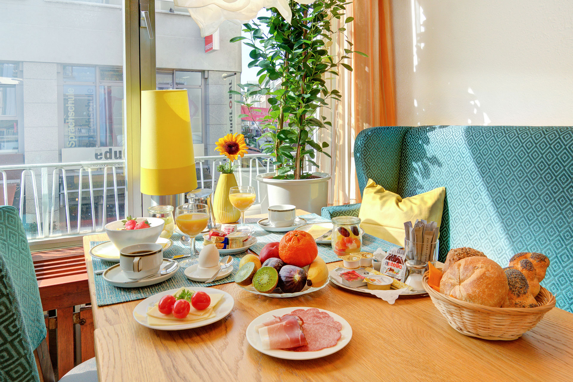 reichhaltig gedeckter frühstückstisch mit sonnenblume und türkise möbel in hotel
