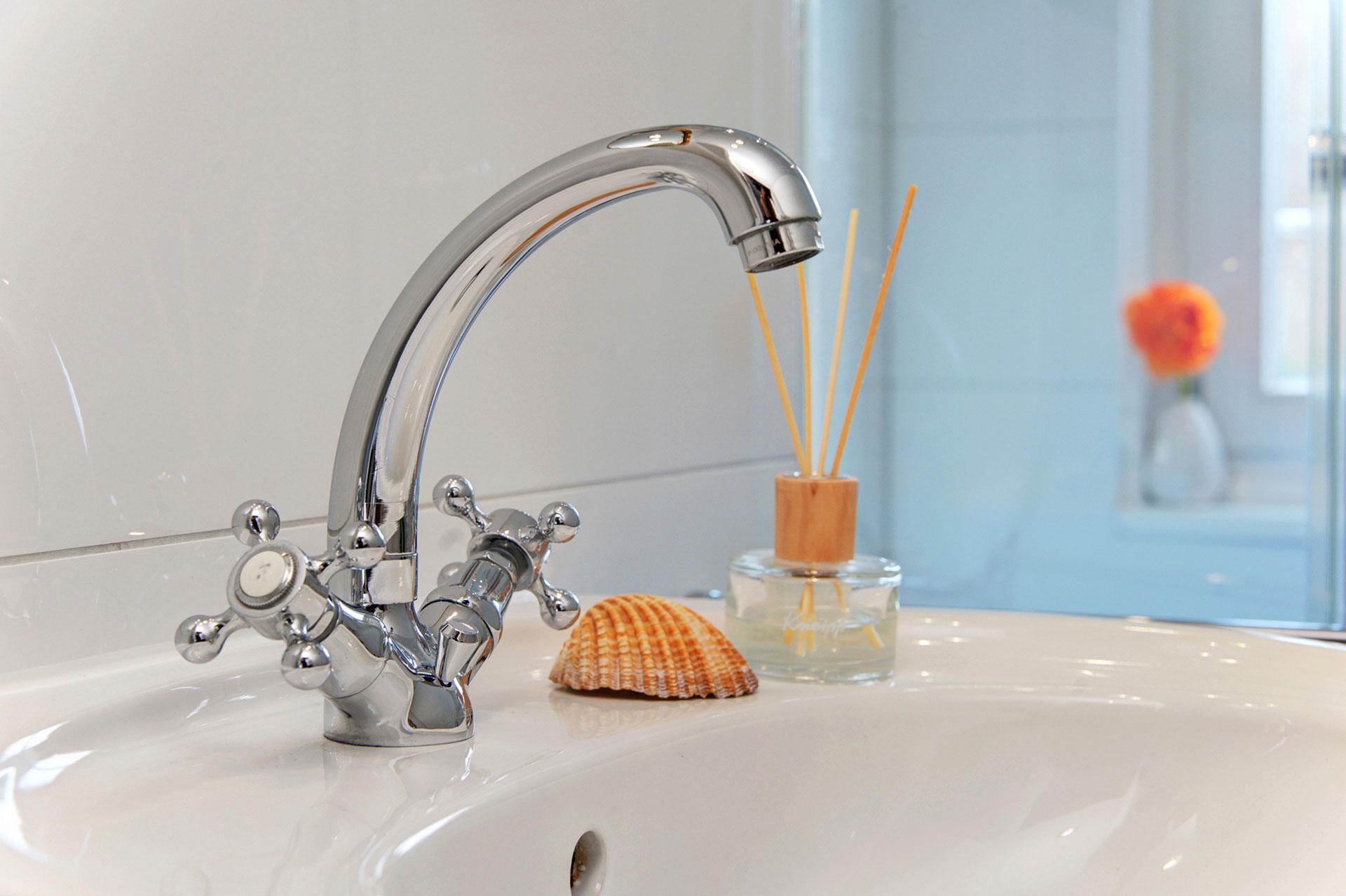 wasserhahn von waschbecken mit muschel duftspender und gerbara in ferienhaus