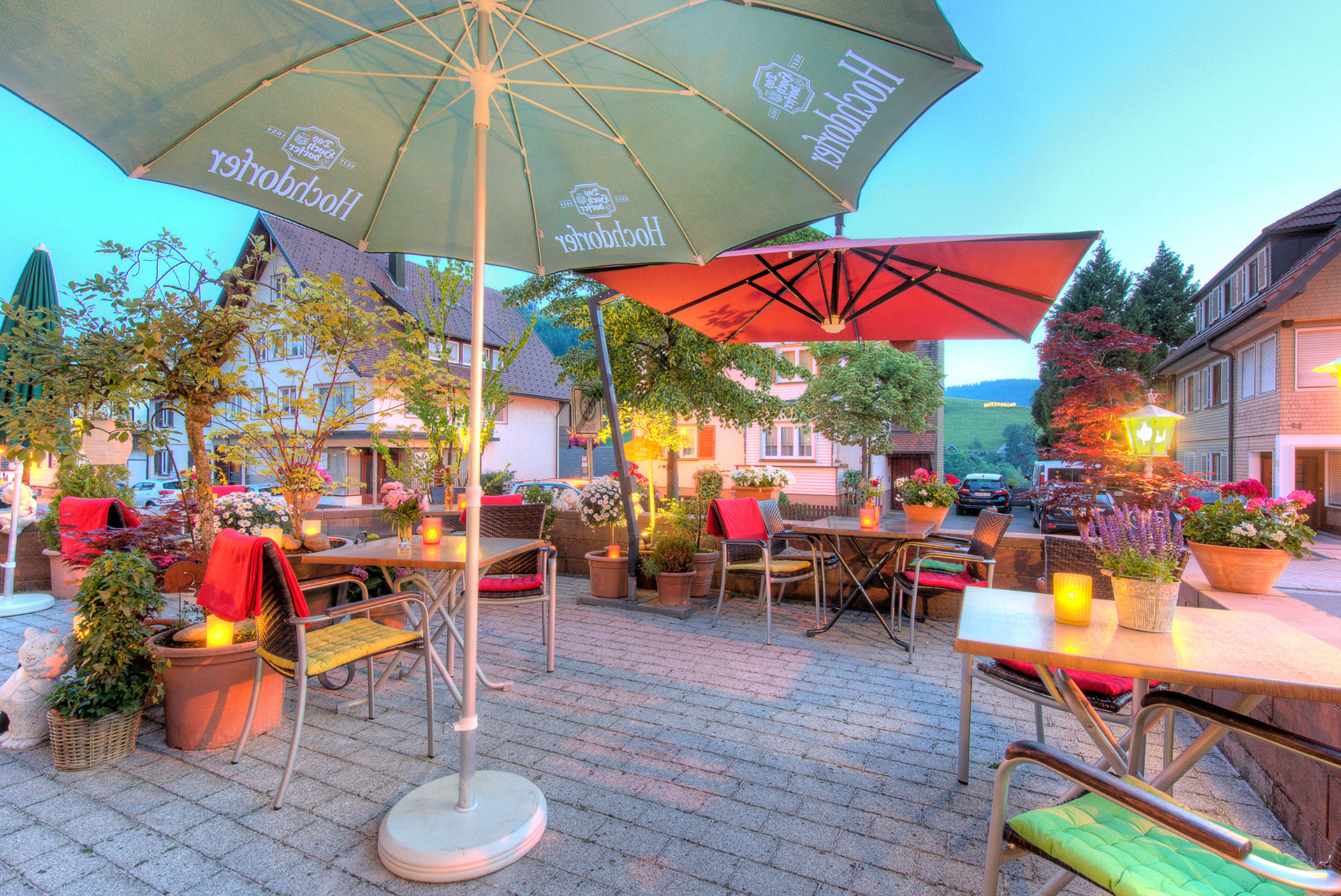 hotelfoto biergarten im kerzenschein mit blick auf rote sonnenschirme