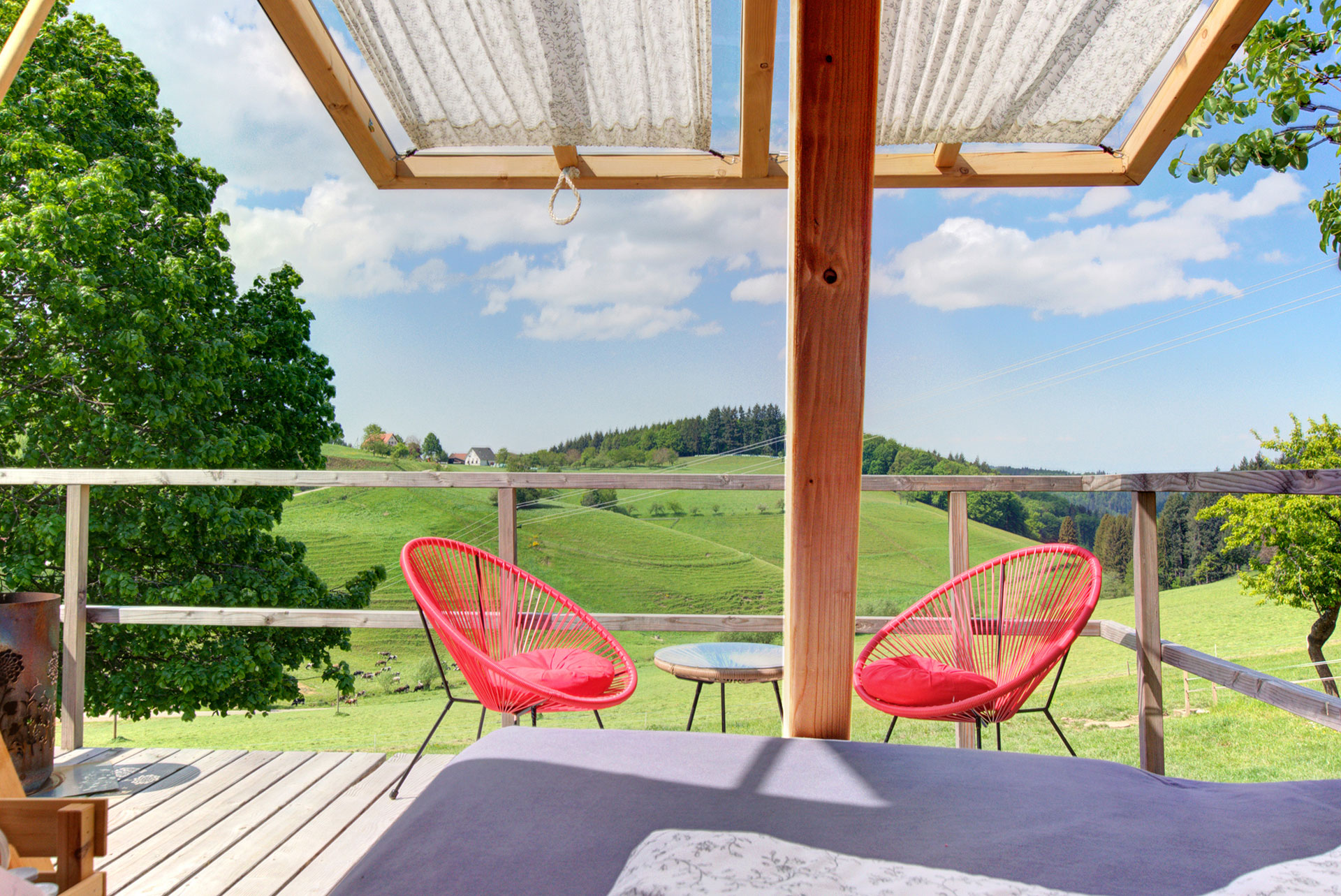 terasse vom holzzelthaus mit roten stühlen und blick auf schwarzwaldlandschaft