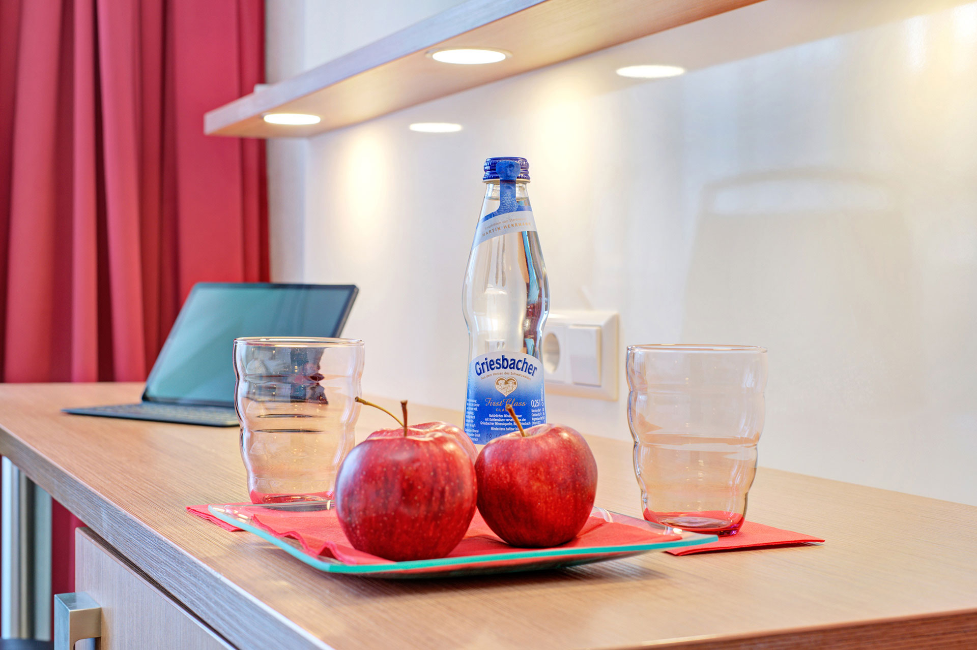 gecke aus mineralwasser mit gläser und äpfel in schale in hotel