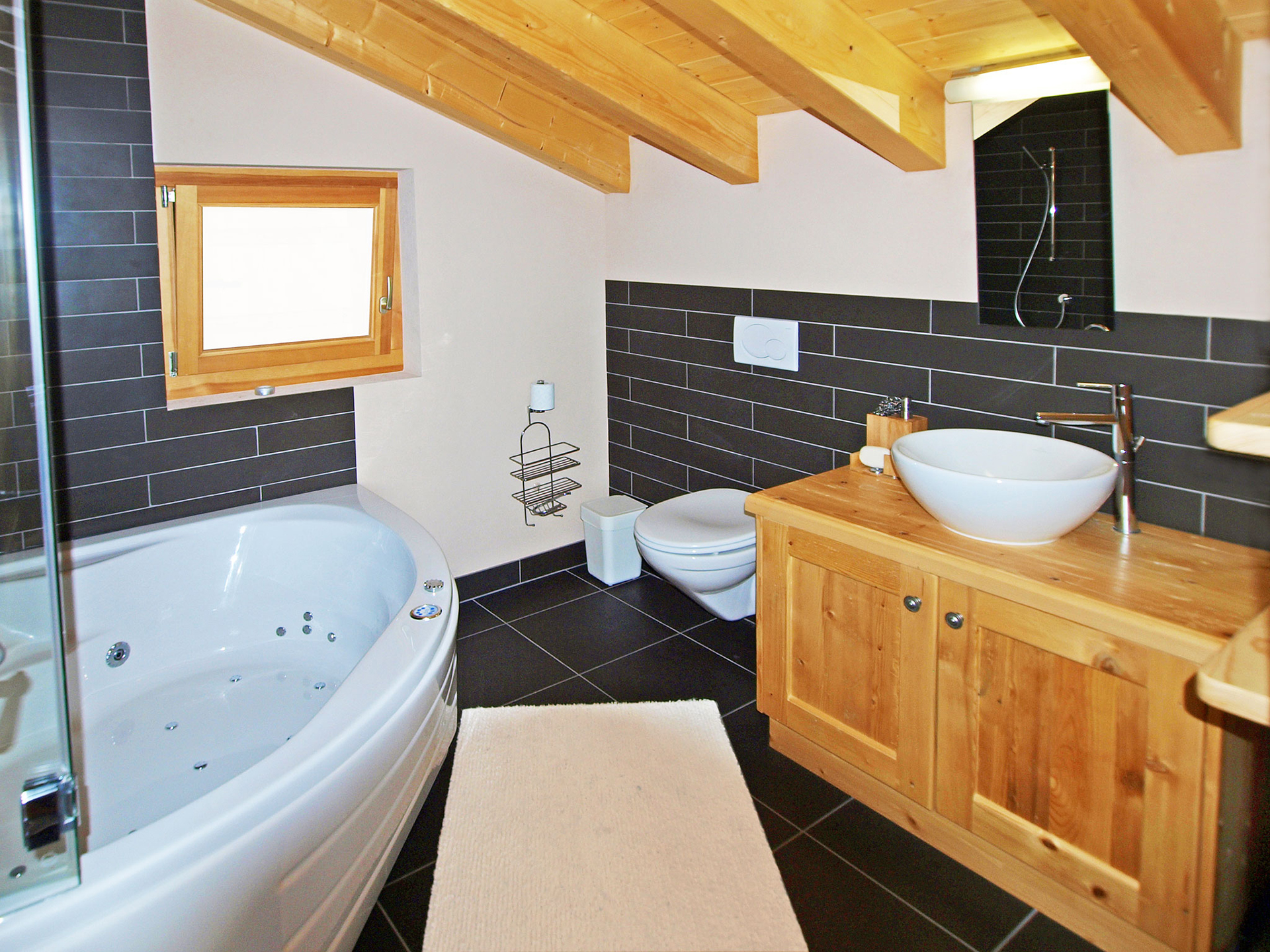 Helles, modernes Badezimmer mit schwarzem Steinboden/ -wand und Holzelementen in einer Ferienwohnung, Fenster geöffnet mit bildbearbeitung