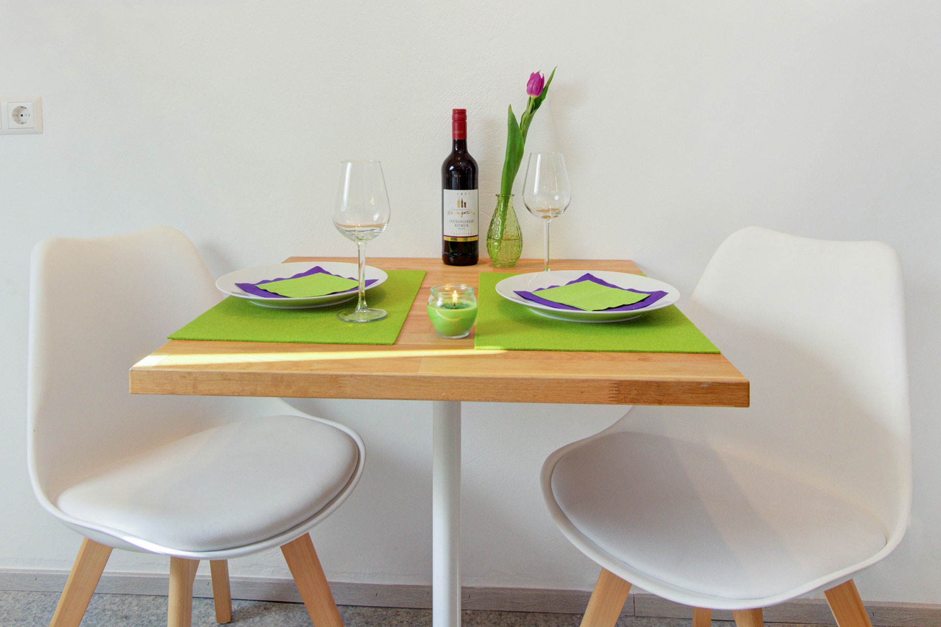 fotografin dekoriert tisch grün eingedeckt mit tulpe und weinflasche