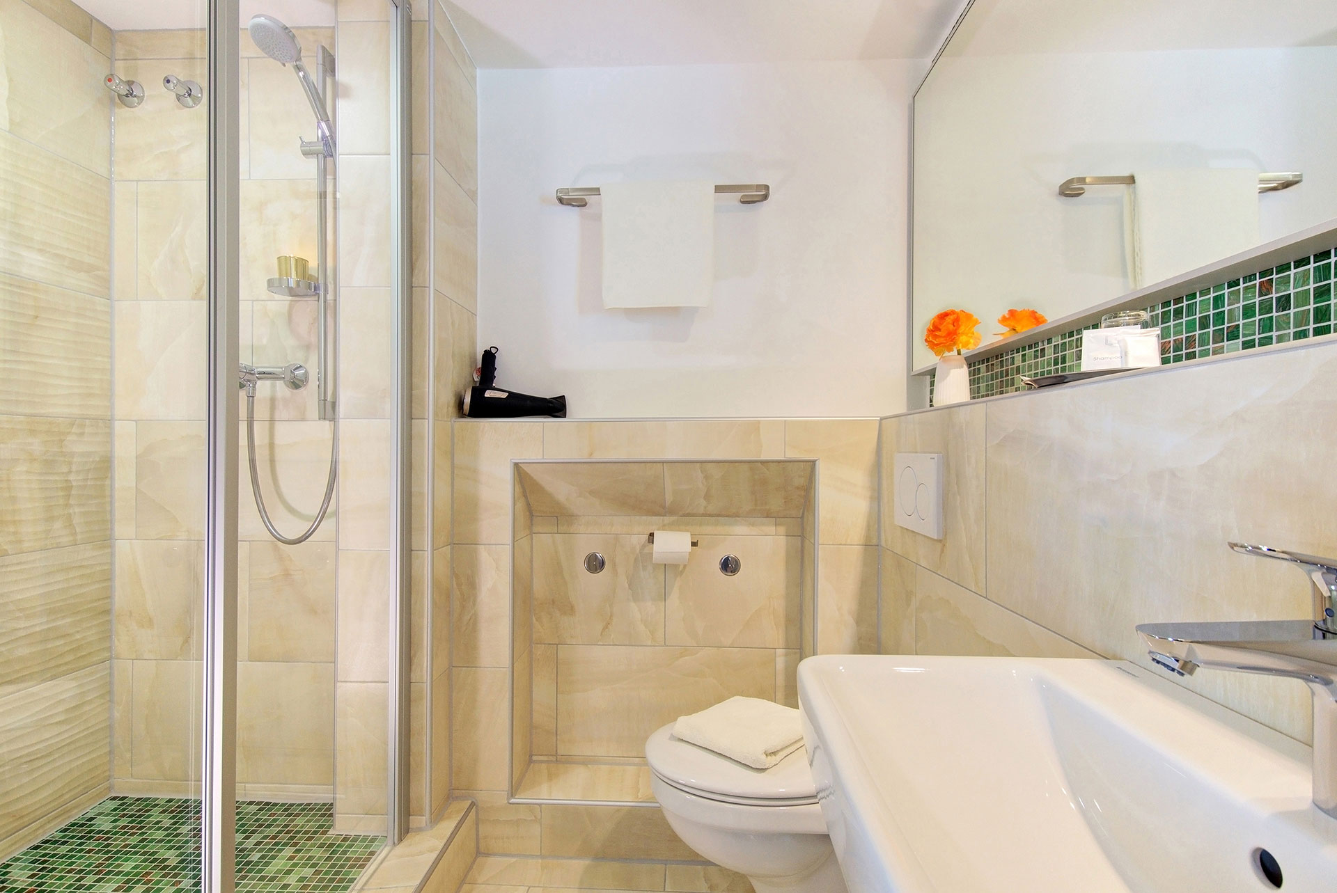 hotelfotograf Badezimmer frontal mit blick auf fön und kleine orangefarbene blume