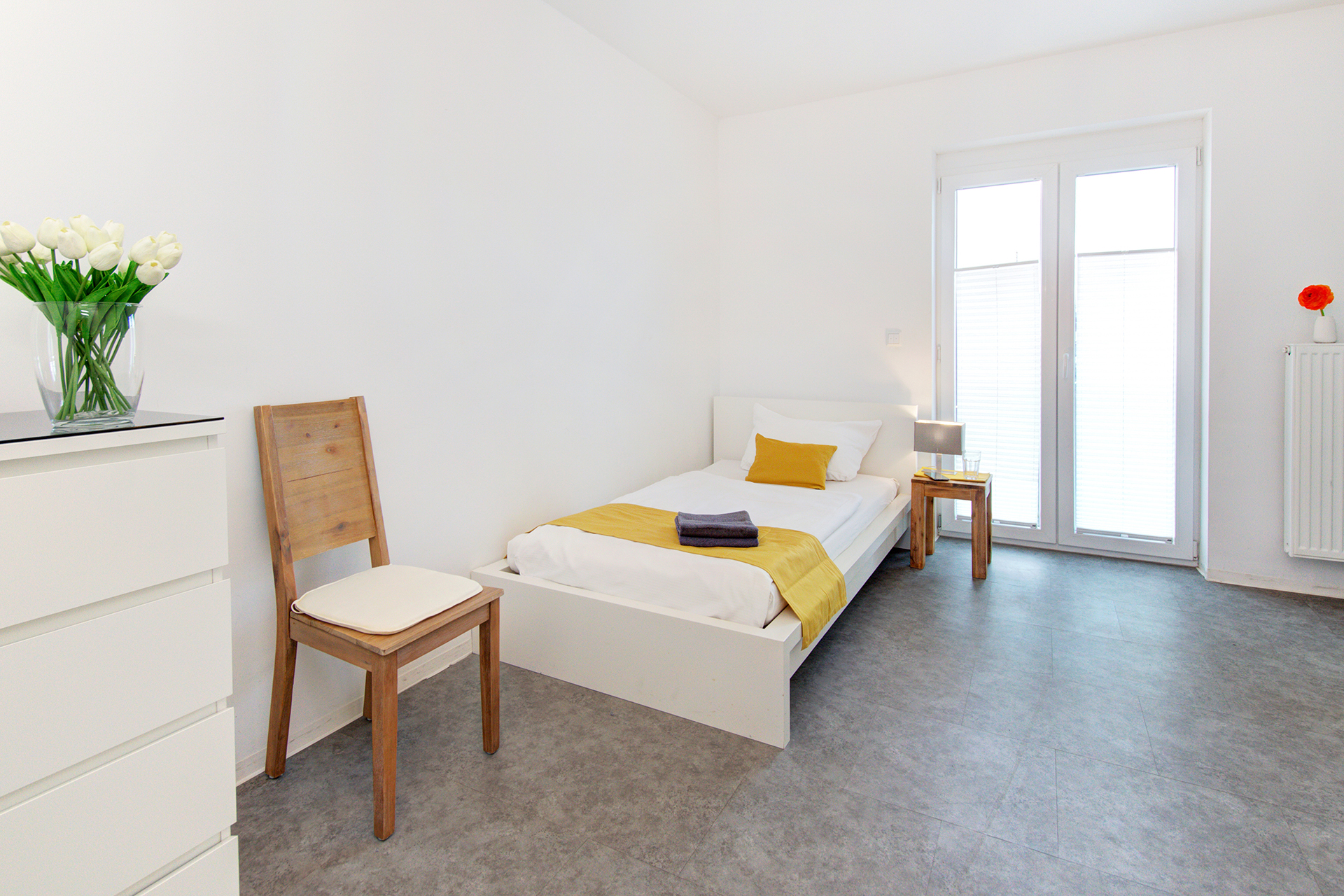 monteurzimmer fotografieren einzelbett vor fenster mit stuhl