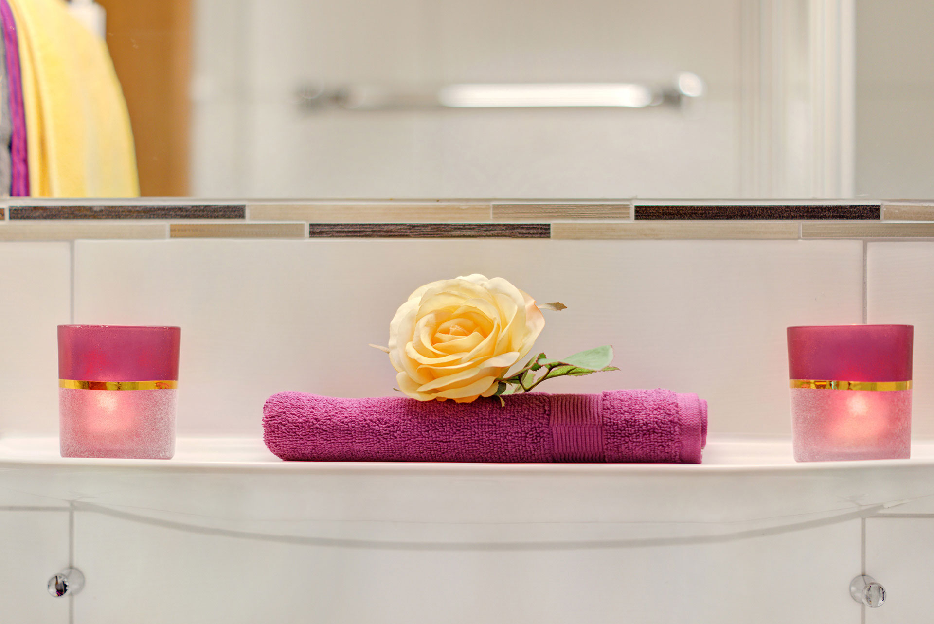 waschbeckenablage mit lila handtuch und gelber rose in ferienwohnung