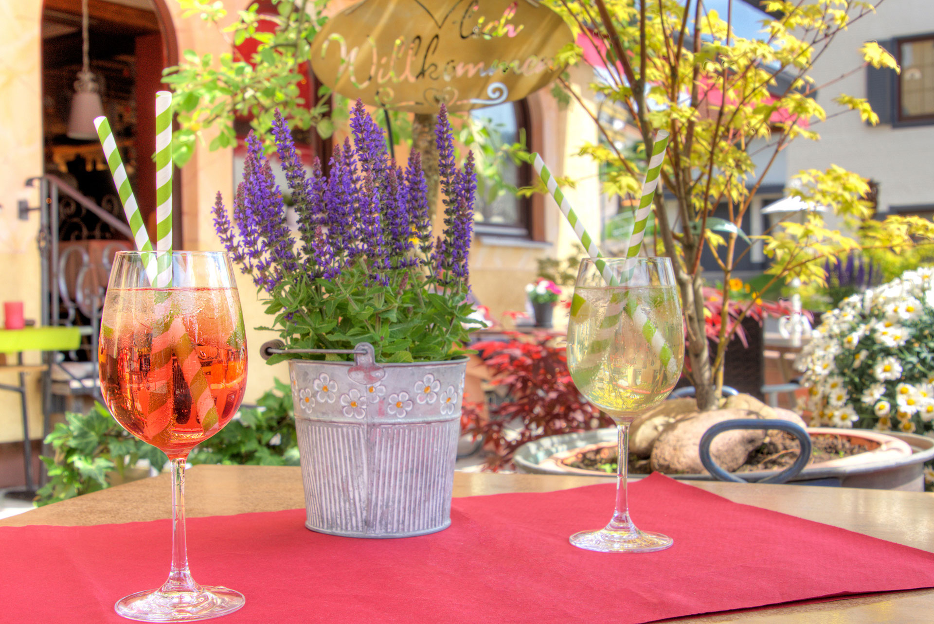 hotelfoto biergarten mit detailblick auf tisch mit zwei frischen getraenken sowie lavendeltoepfchen