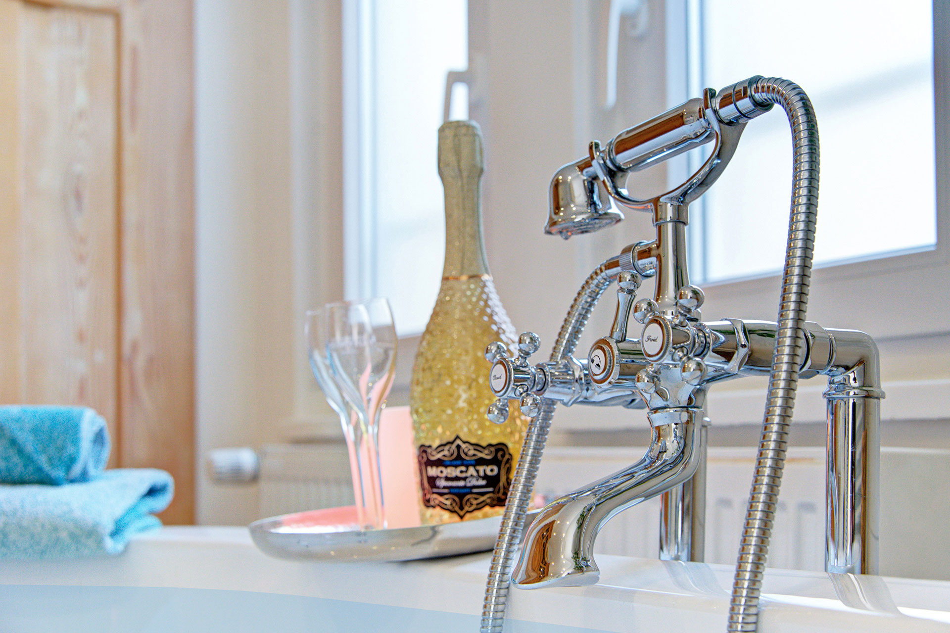 alter wasserhahn von badewanne mit sekt und gläser in ferienhaus