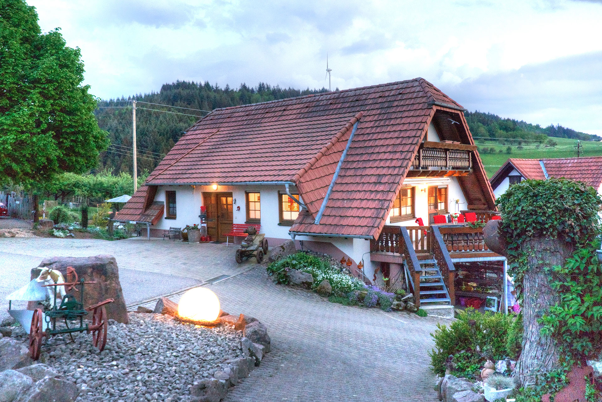 magisches licht am ferienhaus am abend mit erleuchteten fenstern und kugel im vordergrund