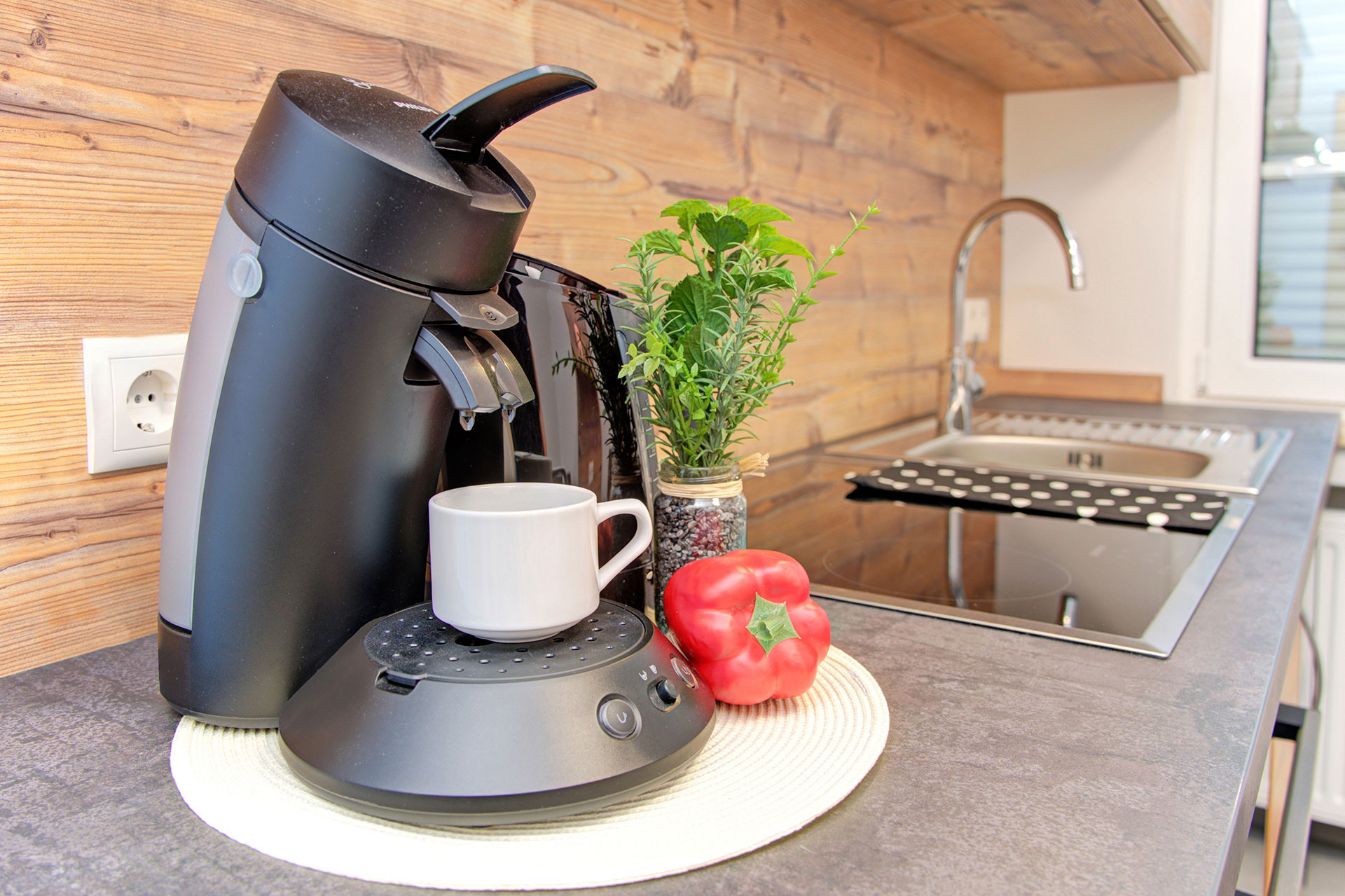 kombination aus espressomaschine kräuter paprika im hintergrund wasserhahn in ferienwohnung