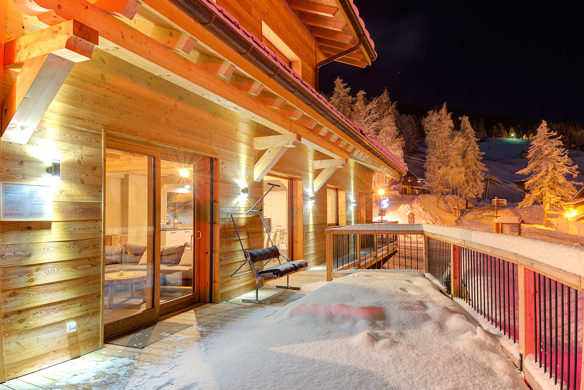 Schneeterrasse mit Blick zum Wohnraum im Chalet Ski Dream am Abend 