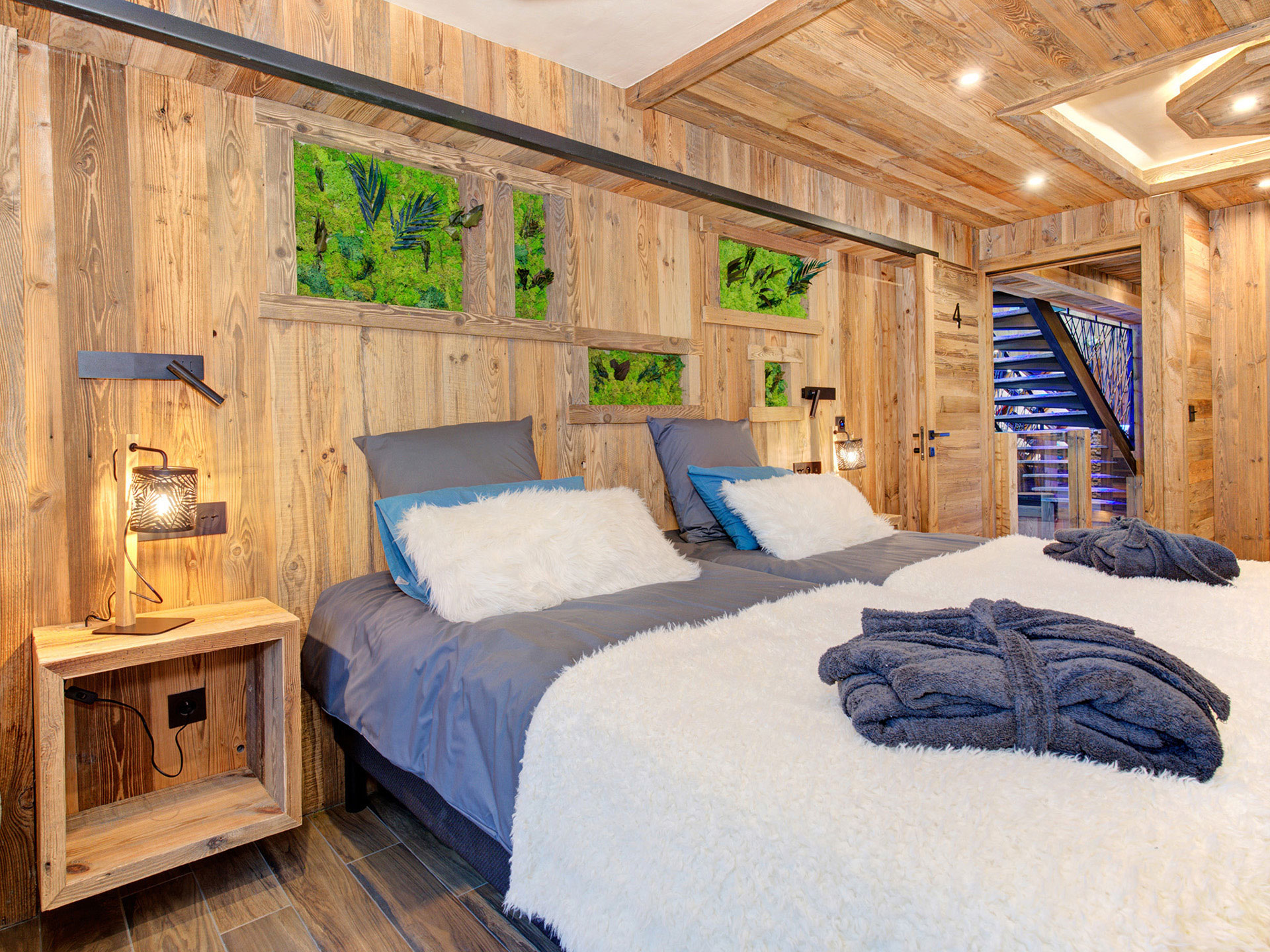 Schlafzimmer aus Holz mit grauer Bettwäsche Bademäntel und weisser Überdecke