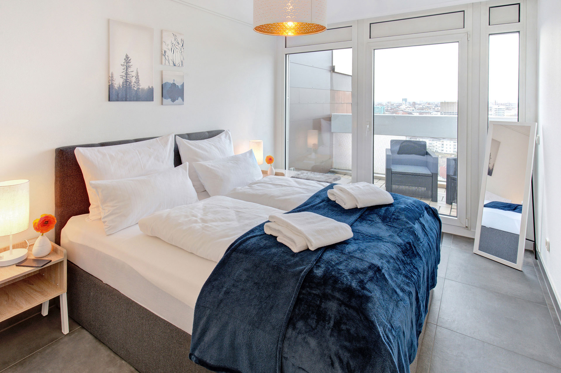 schlafzimmer mit boxspringbett, blauen decken uns weisen handtüchern - vom fotograf für ferienwohnungen