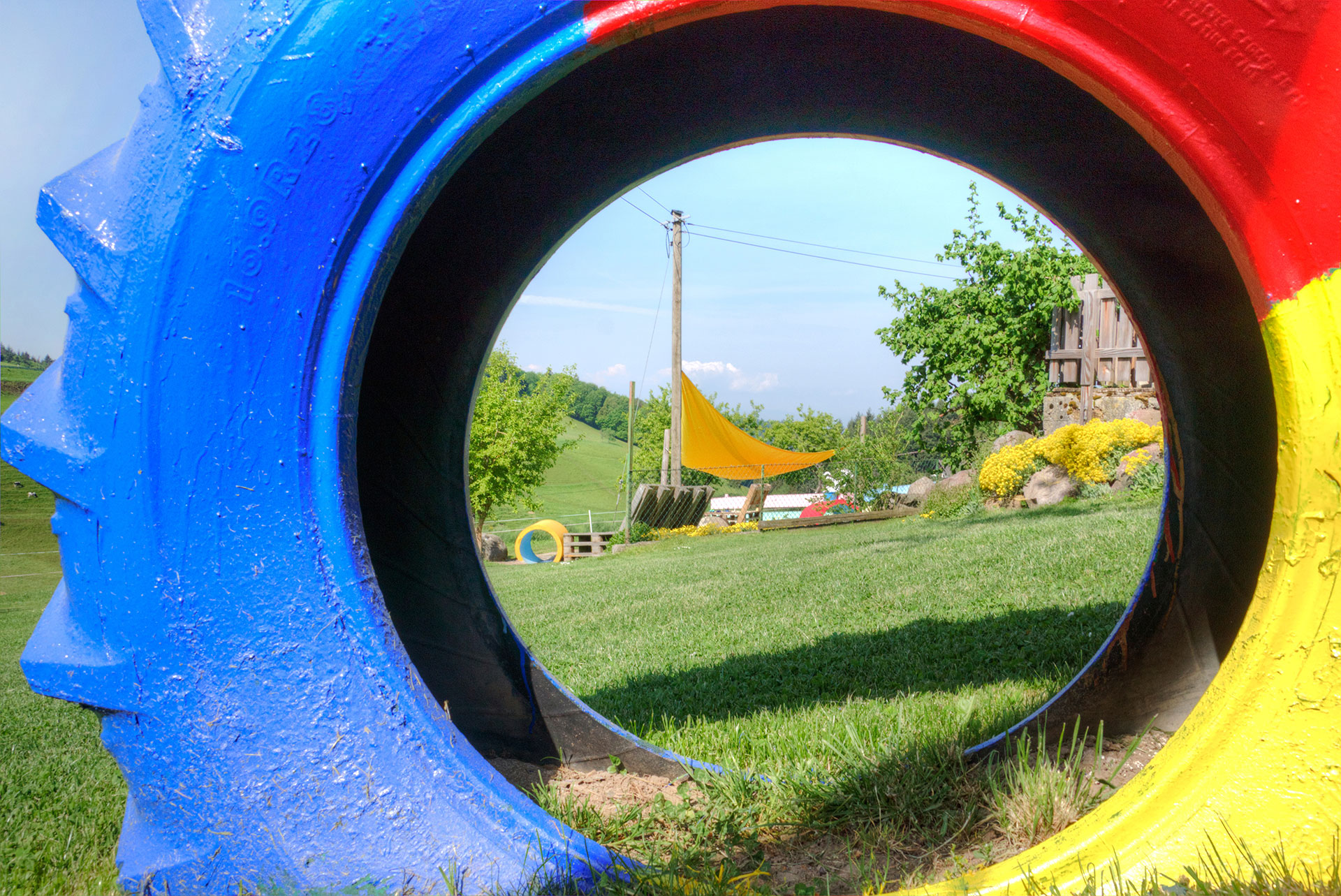 ferienhof foto blick durch farbigen traktoreifen zum spielplatz