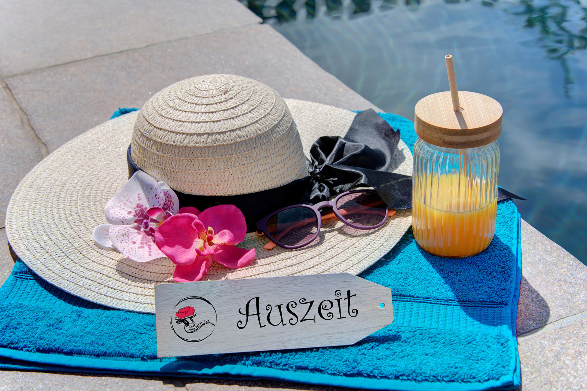 türkises handtuch am pool mit hut und getränk sowie schild auszeit im Ferienhof