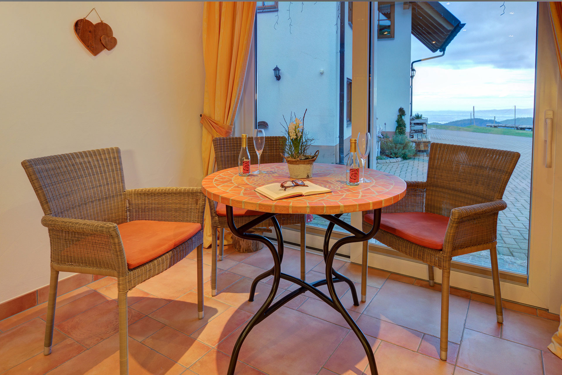 sitzgruppe mit sitzgruppe mit drei korbstühlen mosaiktisch und blaues fensterlicht im wellnessbereich