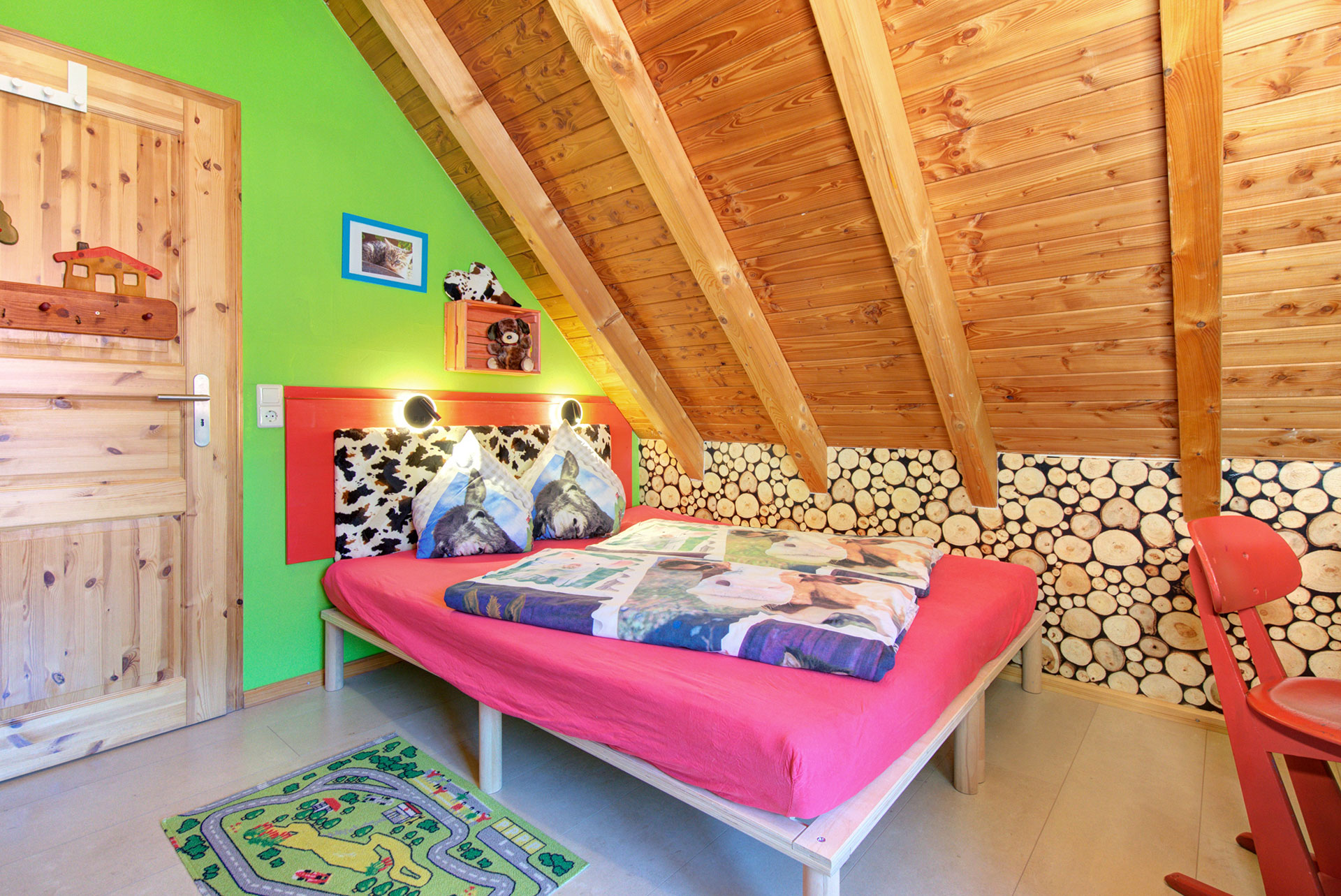 kinderbett vor grüner wand und tiermotive auf bettwäsche im ferienhaus