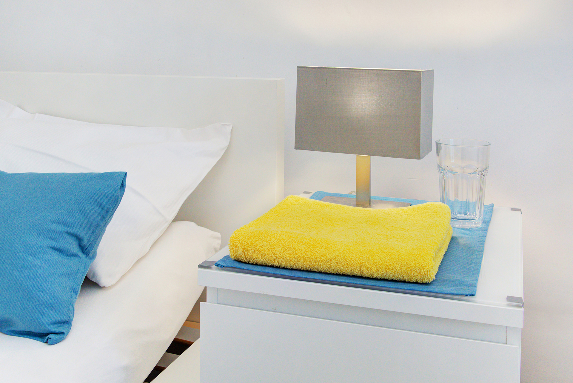 monteurzimmer fotografieren nachttisch mit lampe und gelbem kleinen handtuch