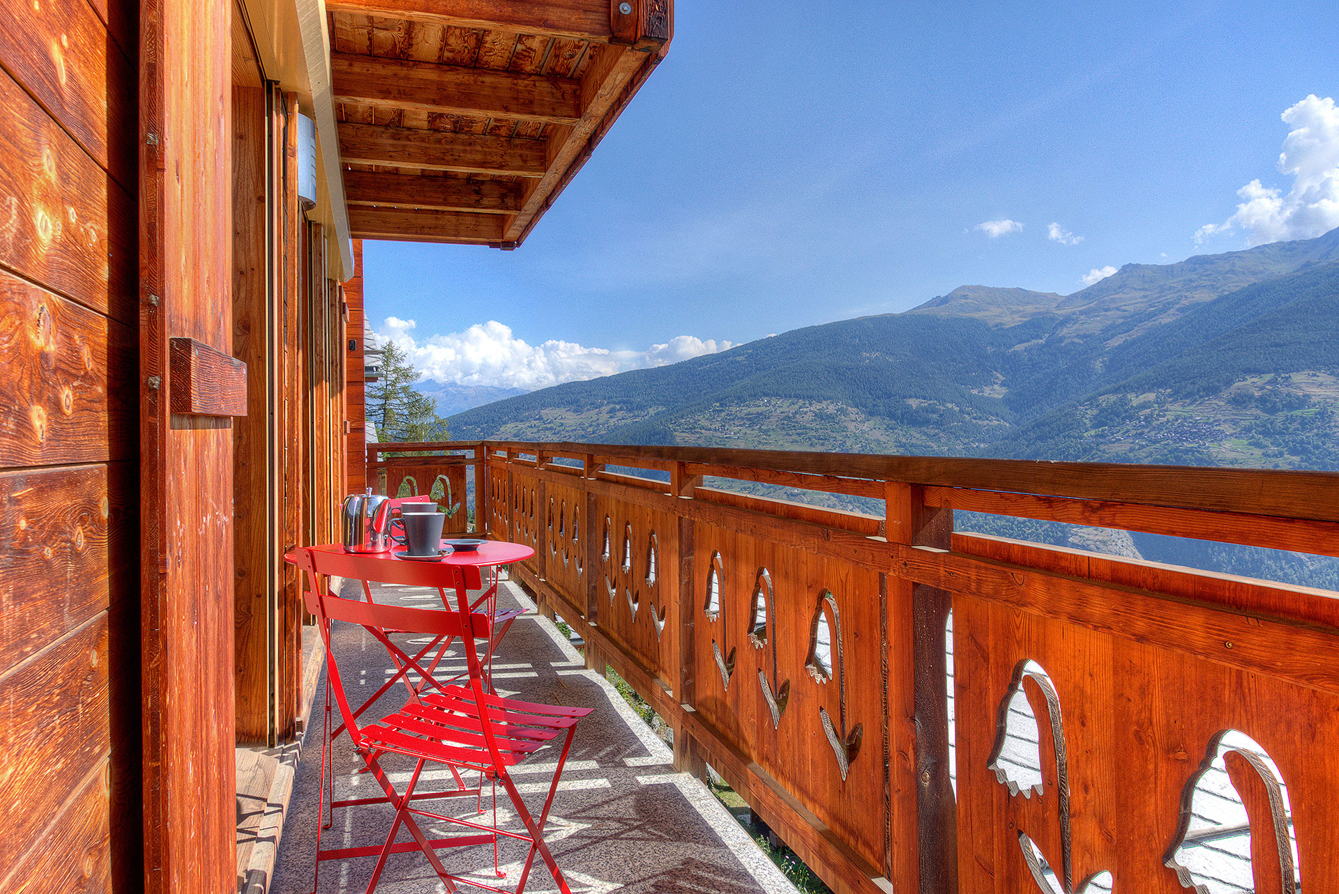 ferienhaus foto balkon von holzchalet mit blick auf die berge und rote tischgarnitur